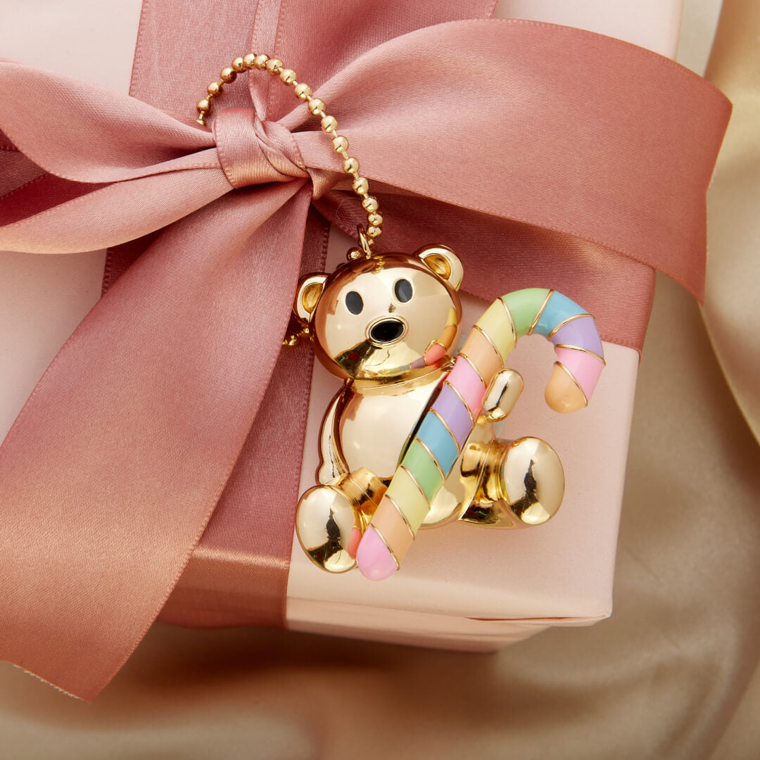 Gold teddy bear bag chain with candy cane on a pink gift box