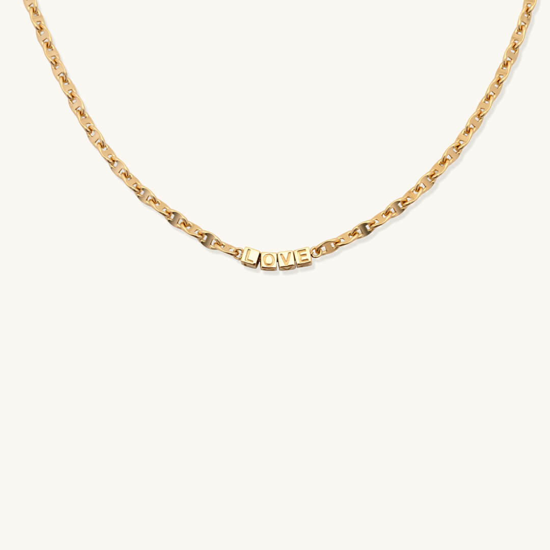 Gold necklace with 'LOVE' pendant on a white background