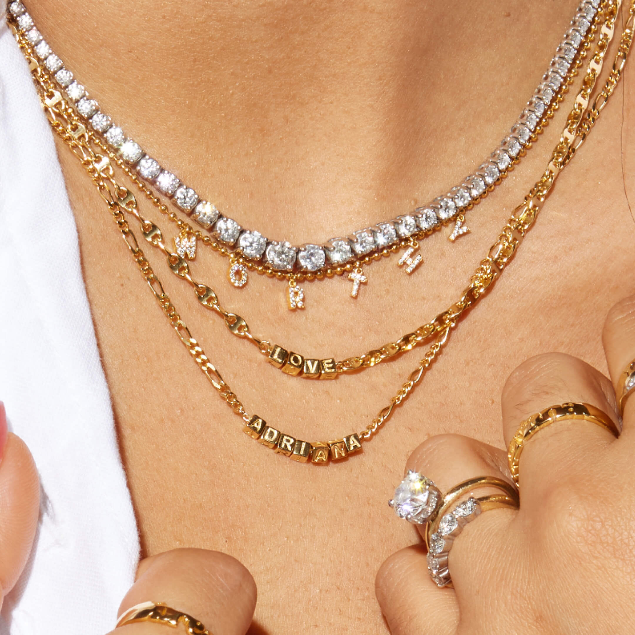 Close-up of a person wearing multiple gold necklaces and rings with visible branding.