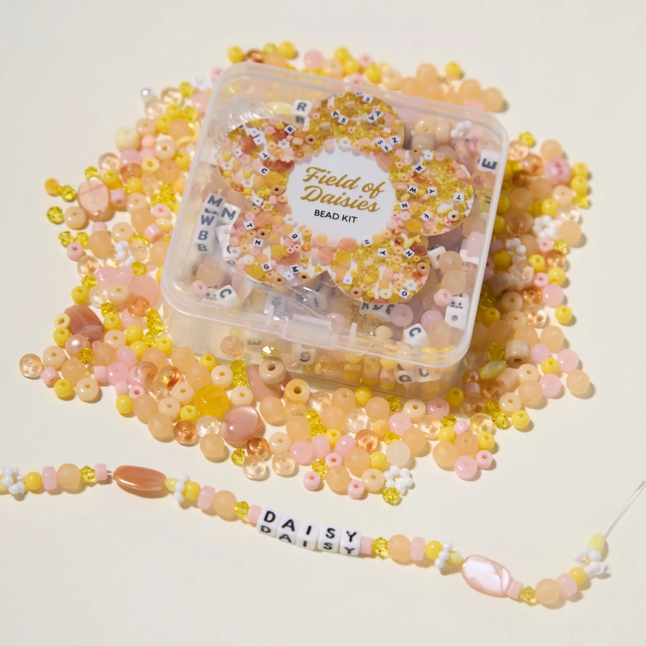 Bead kit with 'Field of Daisies' branding surrounded by yellow and pink beads on a light background