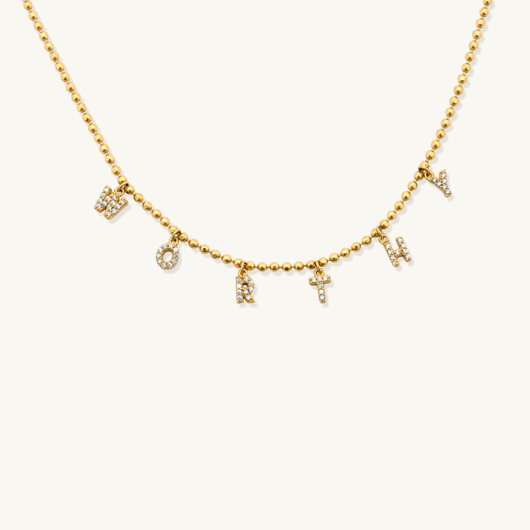 Gold necklace with letter charms on a white background
