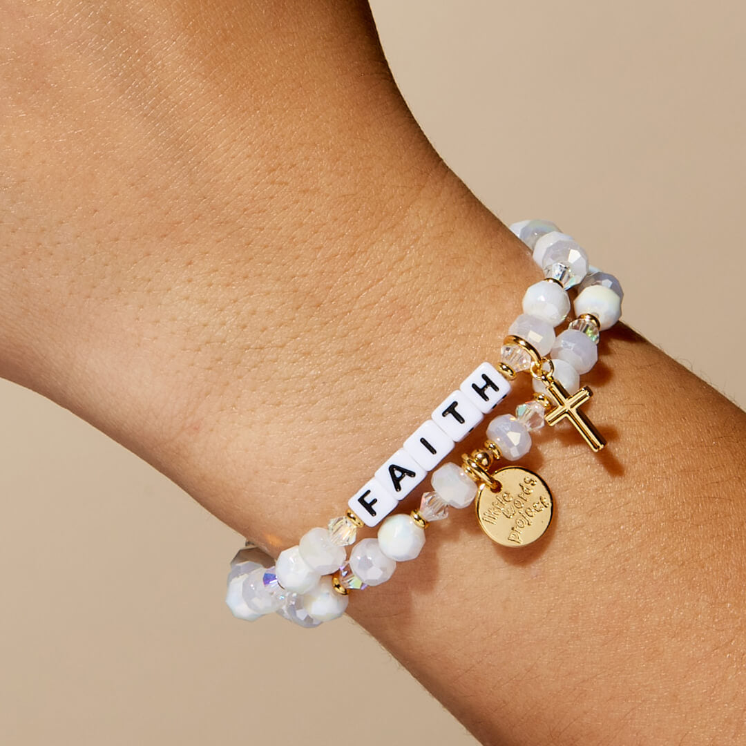 Bracelet with 'FAITH' word on a wrist against a beige background