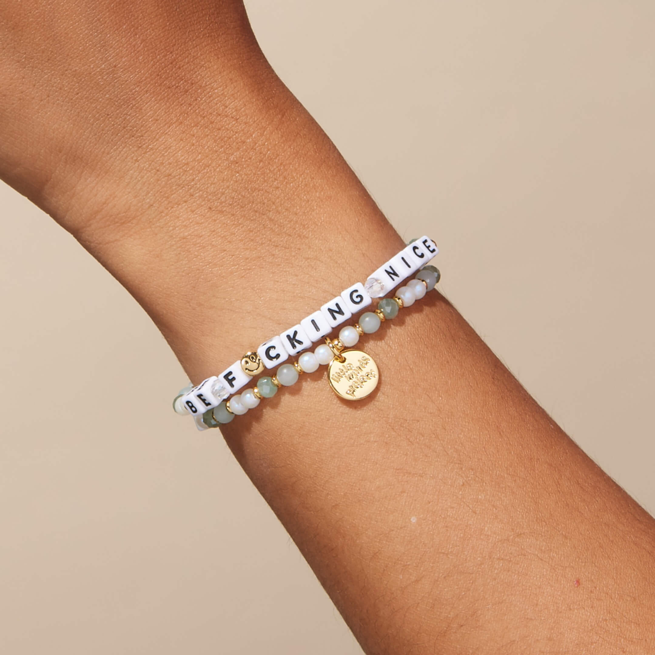 Bracelet with letter beads on a wrist against a beige background
