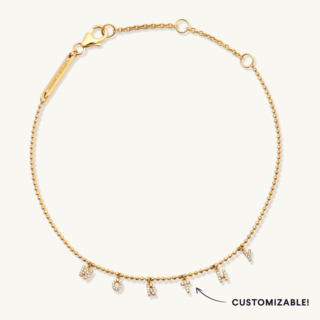 Gold bracelet with customizable charms on a white background