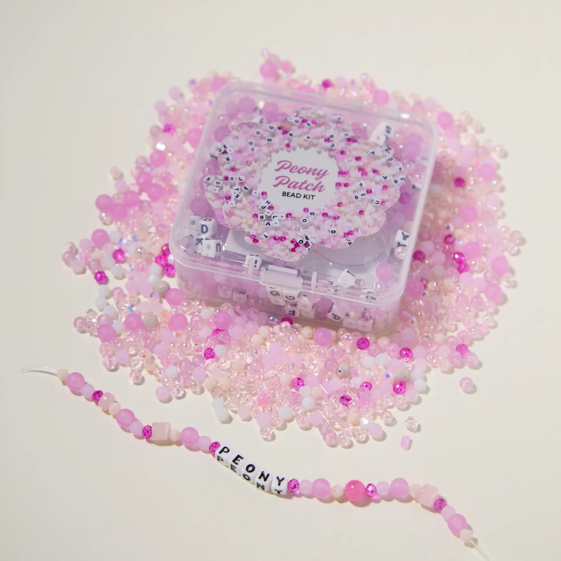 Bead kit with pink beads and a completed beaded bracelet on a light background