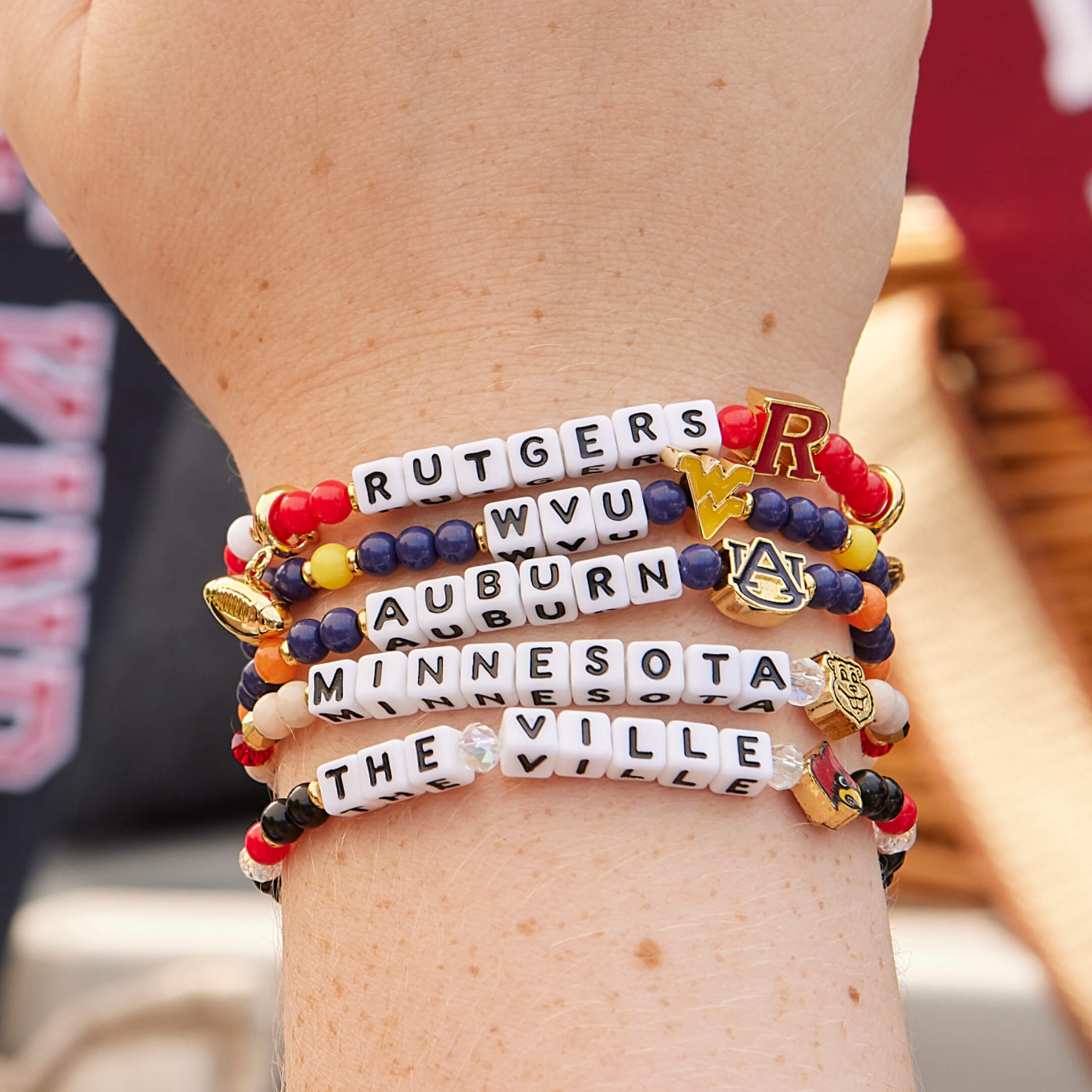 Stack of beaded bracelets with team names on a wrist