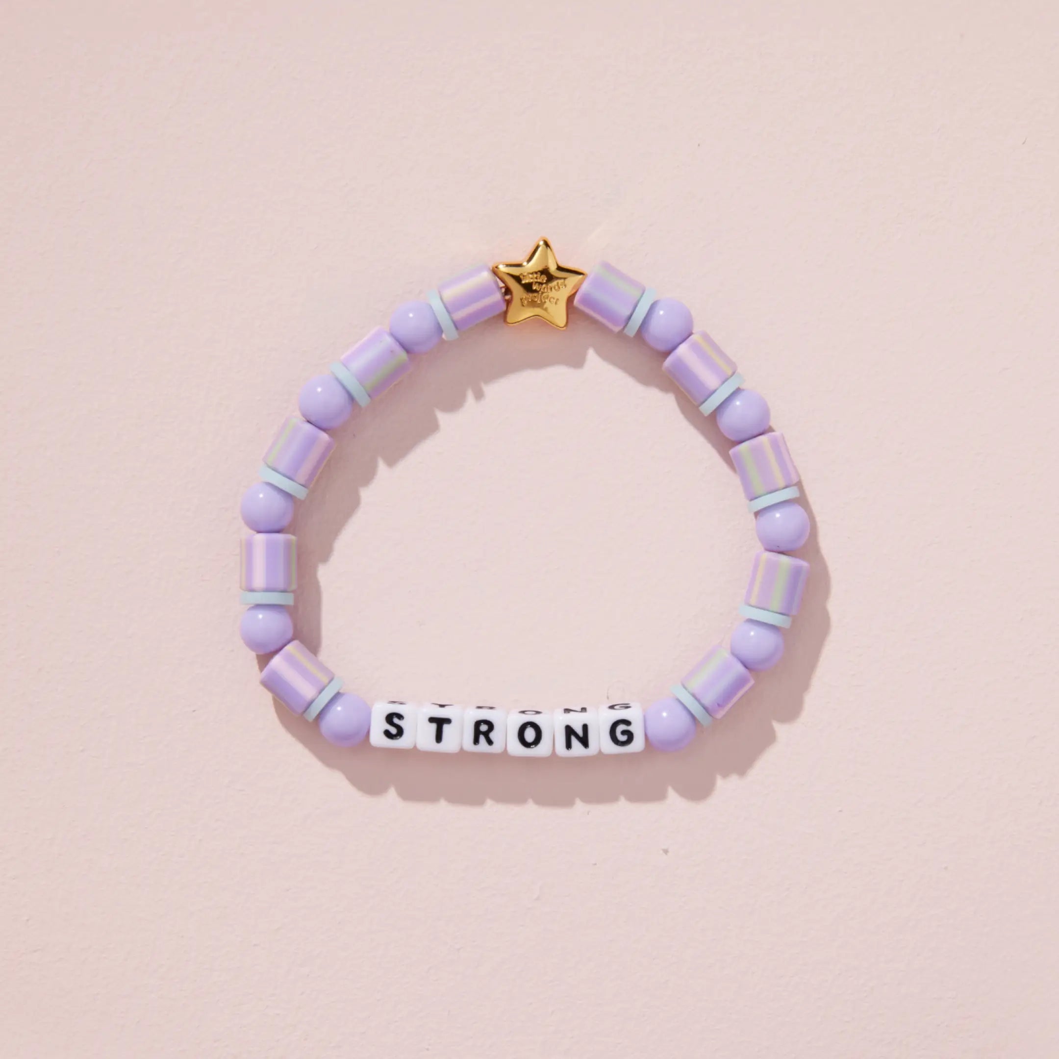 Purple beaded bracelet with a gold star tag on a pink background