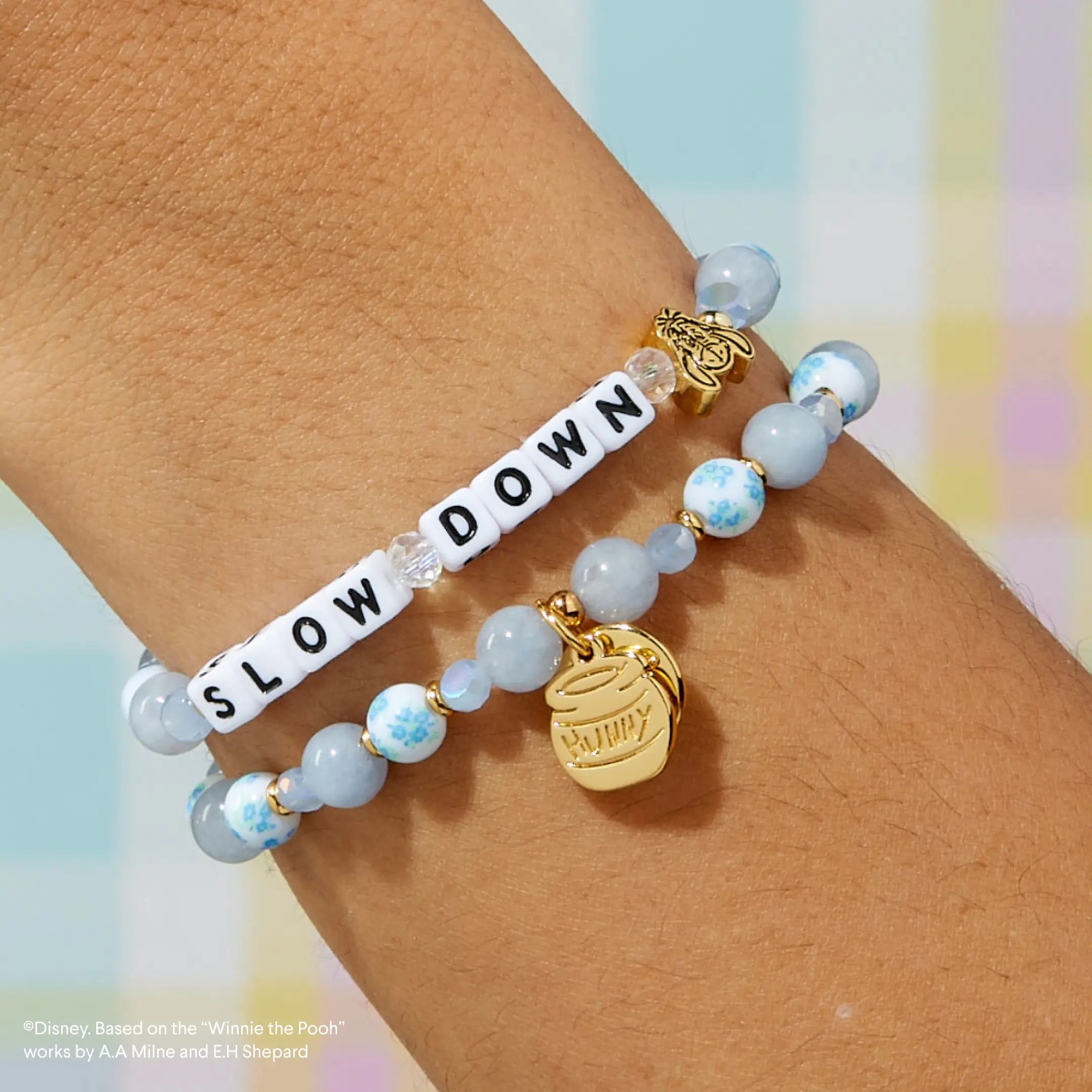 Bracelet with 'SLOW DOWN' on wrist against a colorful background