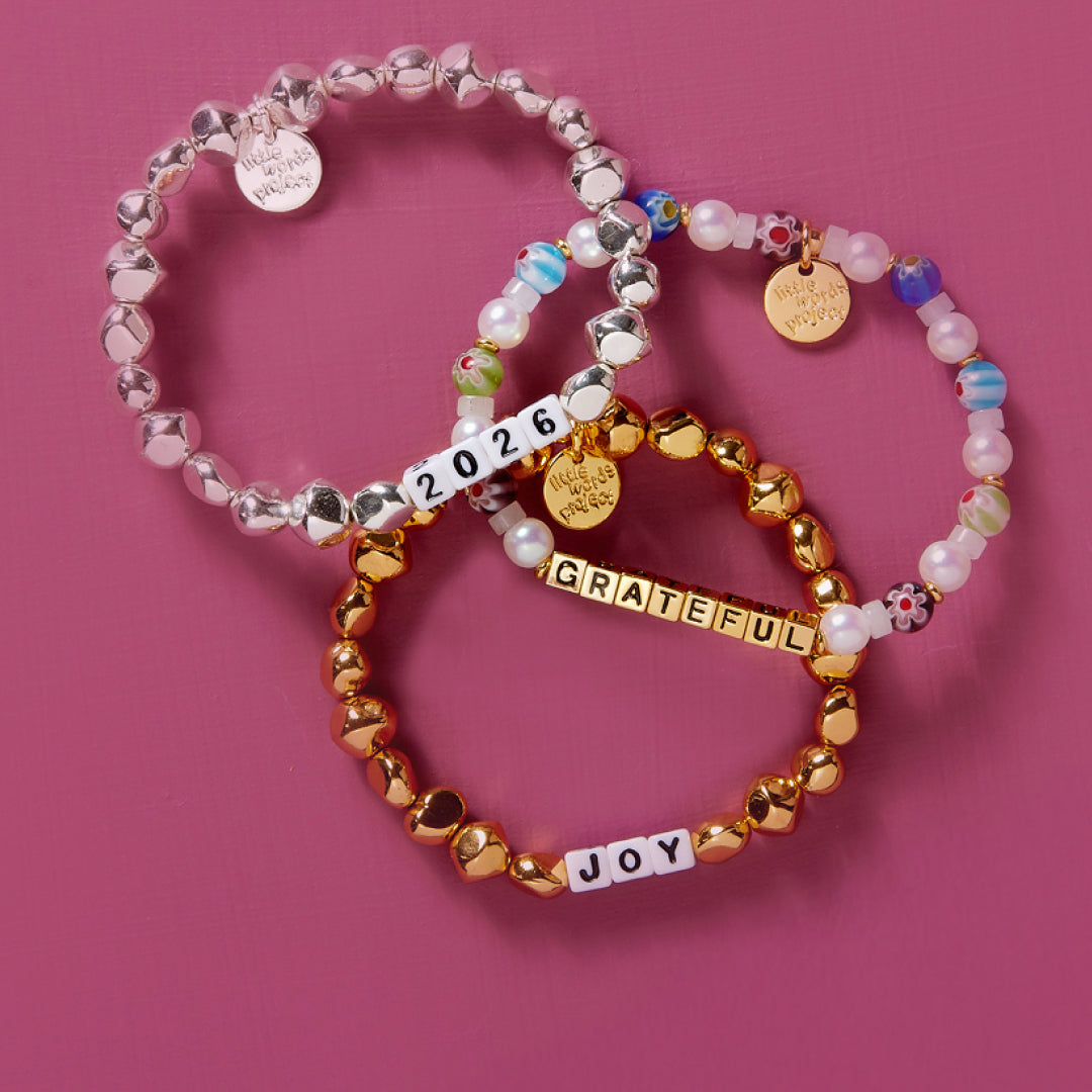 Three beaded bracelets with custom words on a pink background