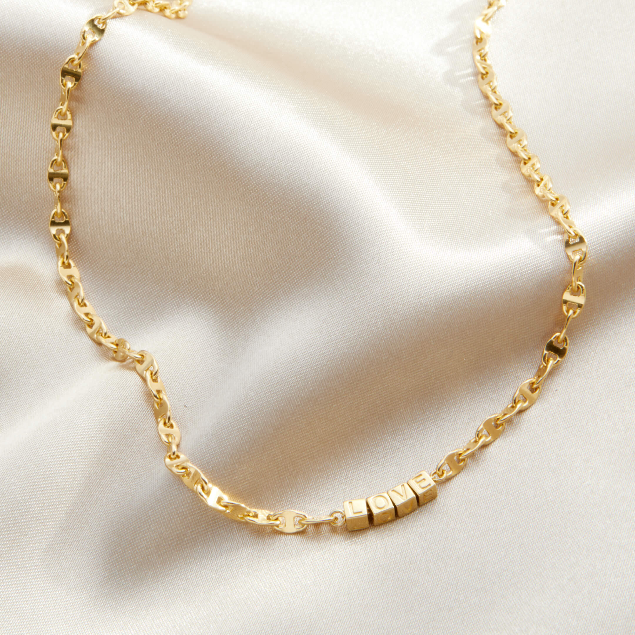 Gold chain necklace on a beige fabric background