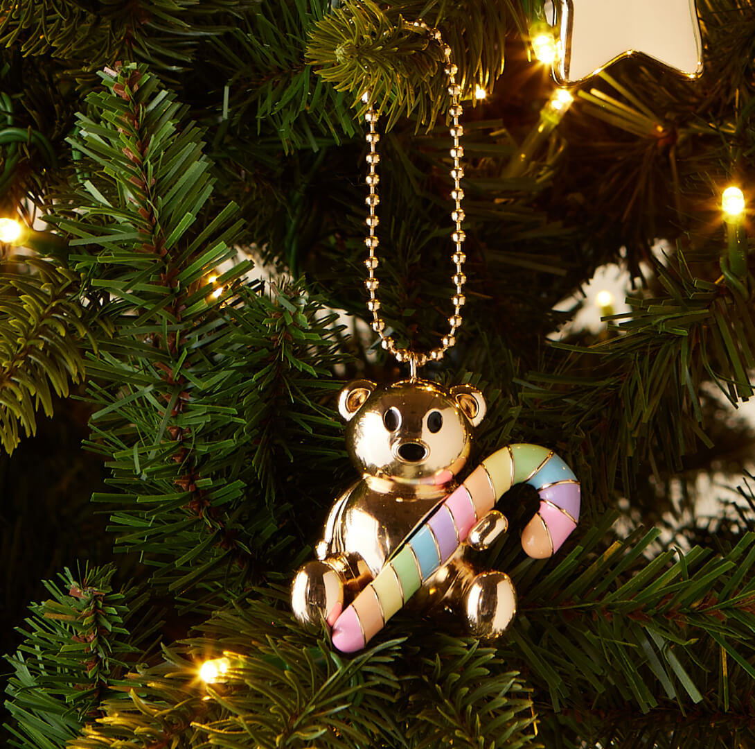Gold teddy bear bag charm with a candy cane on a Christmas tree.