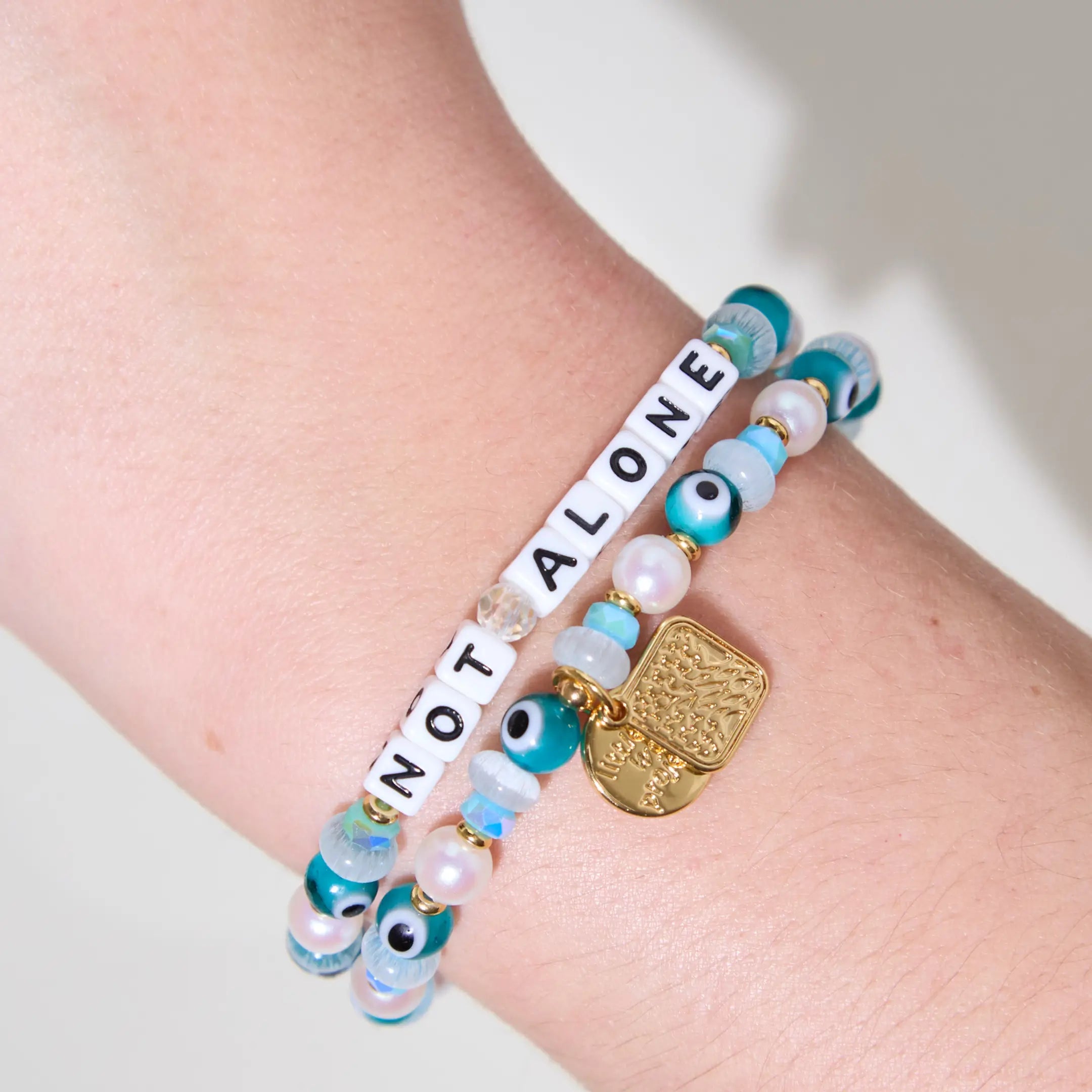 Bracelet with 'Not Alone' message on wrist against a neutral background