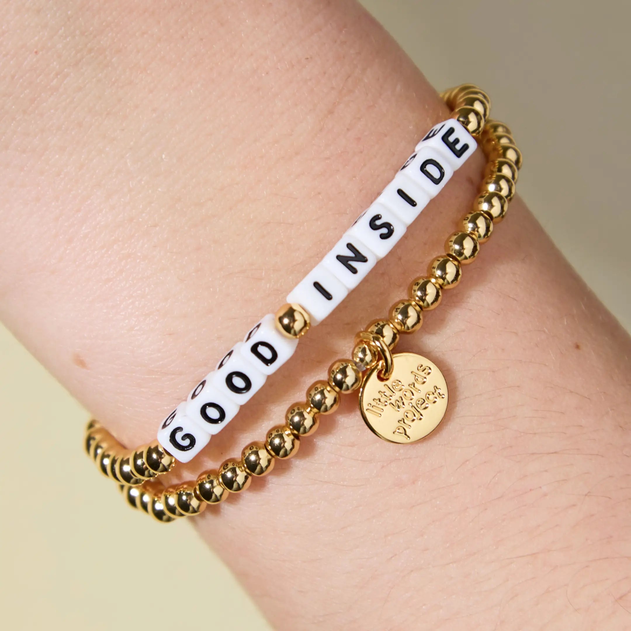 Gold beaded bracelet reading 'Good Inside' on a wrist.