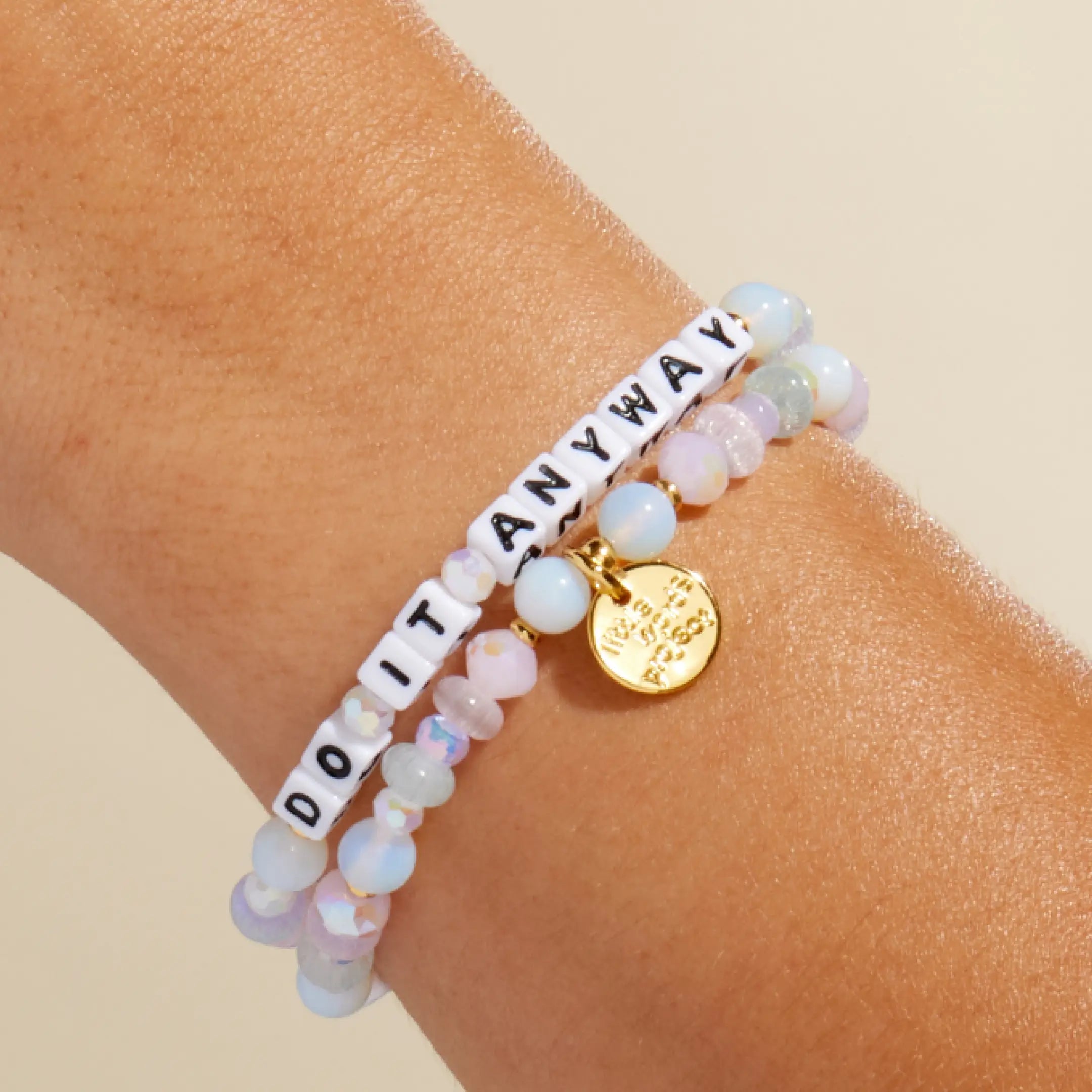 Do It Anyway — on-model wrist shot of beaded word bracelet stacked with other bracelets in pastel and white beads