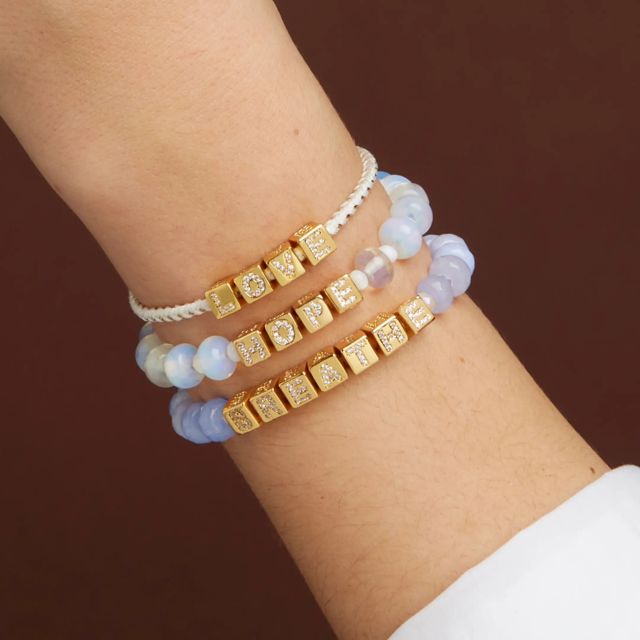 Stack of bracelets on a wrist against a brown background