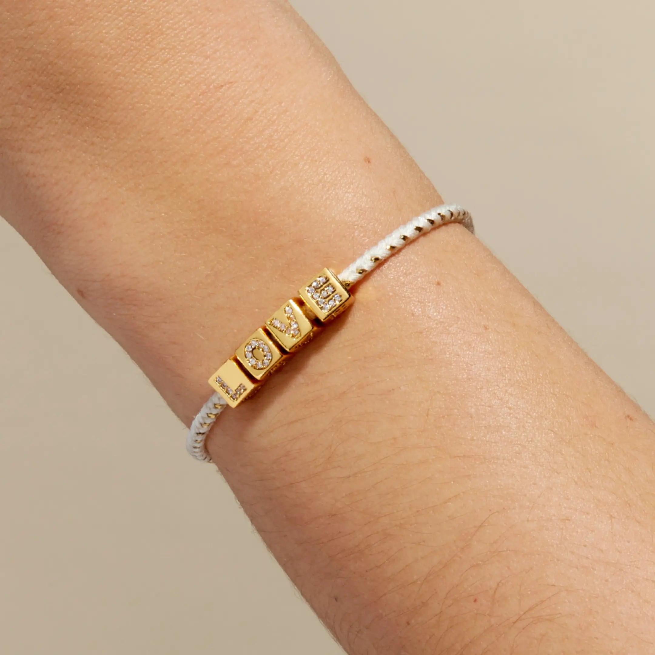 White and Gold bracelet on a wrist against a neutral background