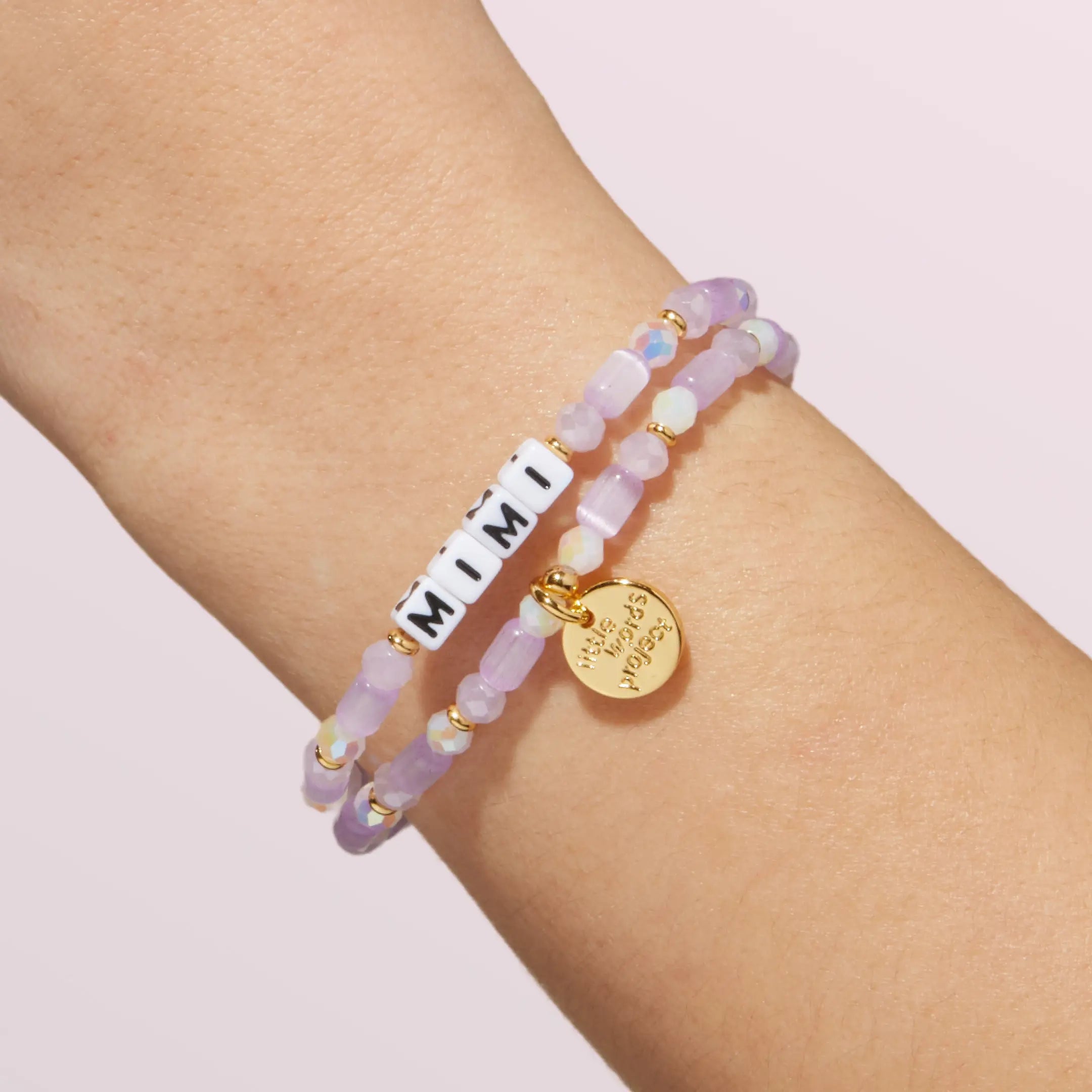 Two beaded bracelets on a wrist with a plain background