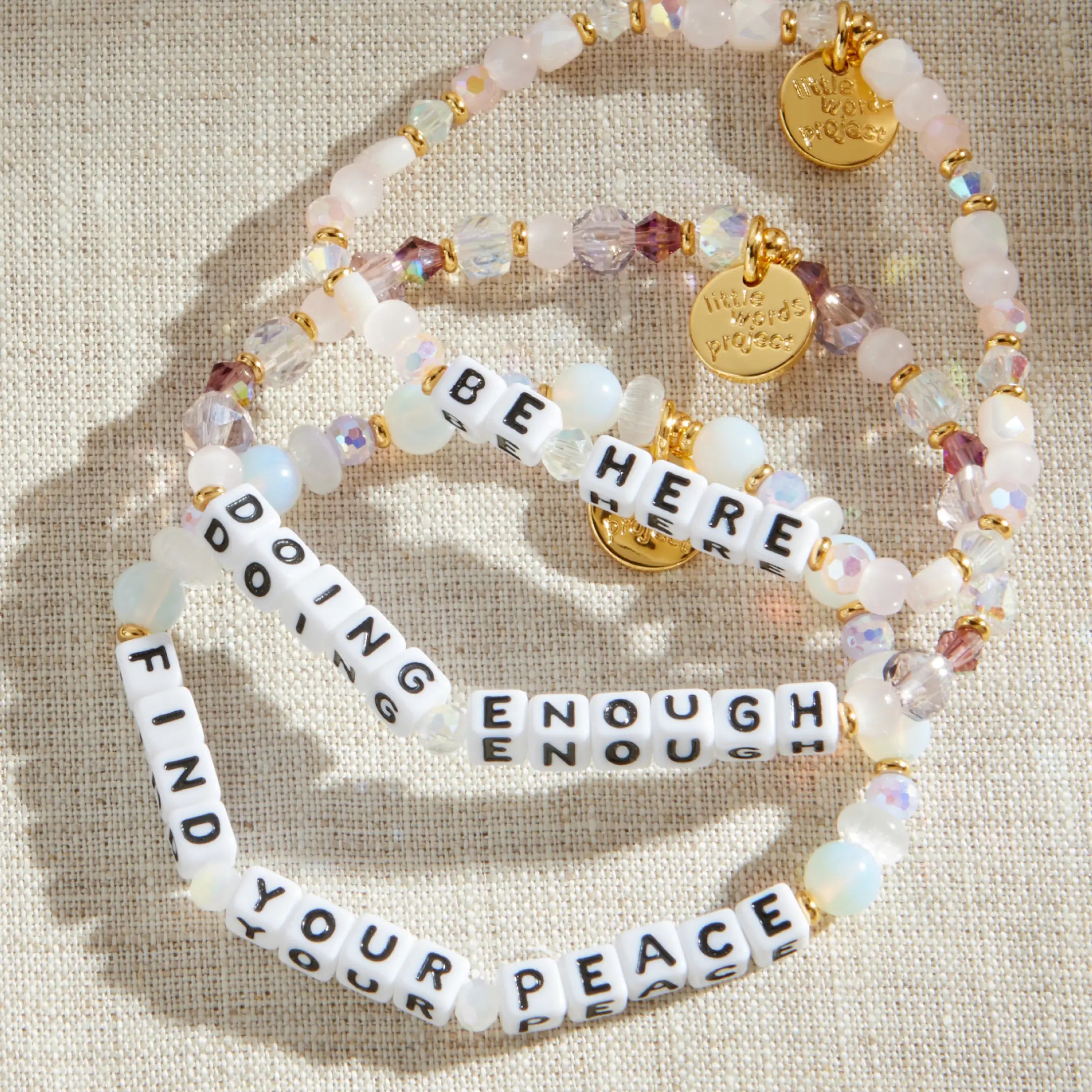 Set of beaded bracelets with inspirational phrases on a beige fabric background