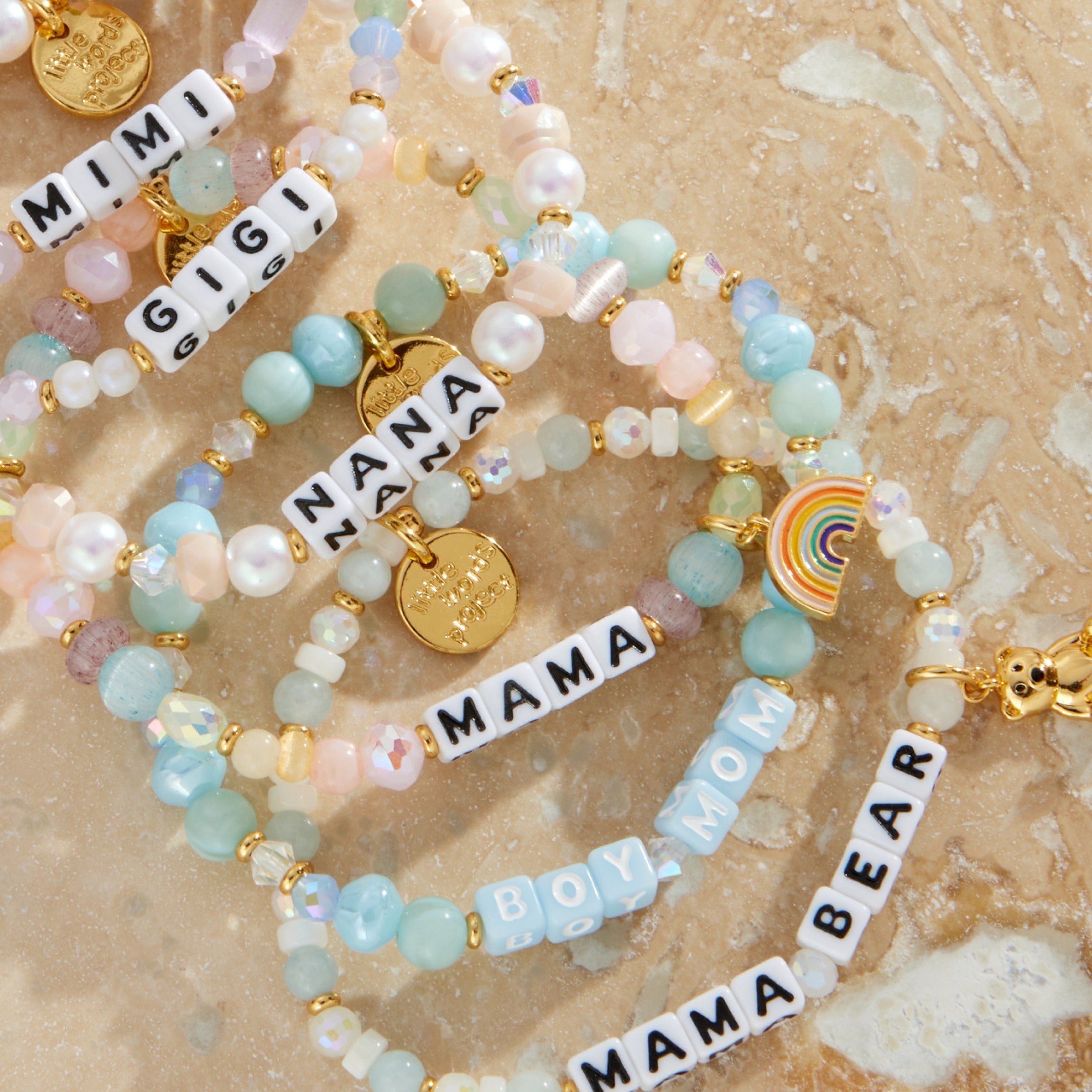 Set of beaded bracelets with charms on a textured beige surface