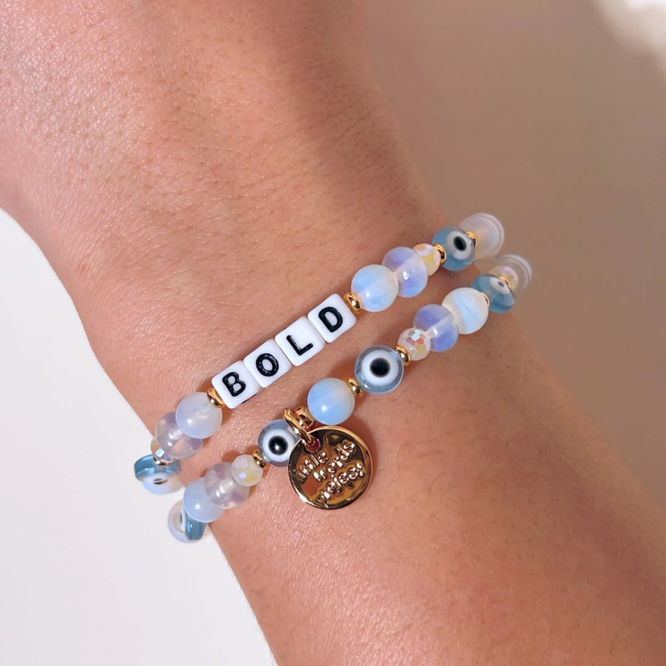 Beaded bracelet with 'BOLD' on a wrist against a neutral background