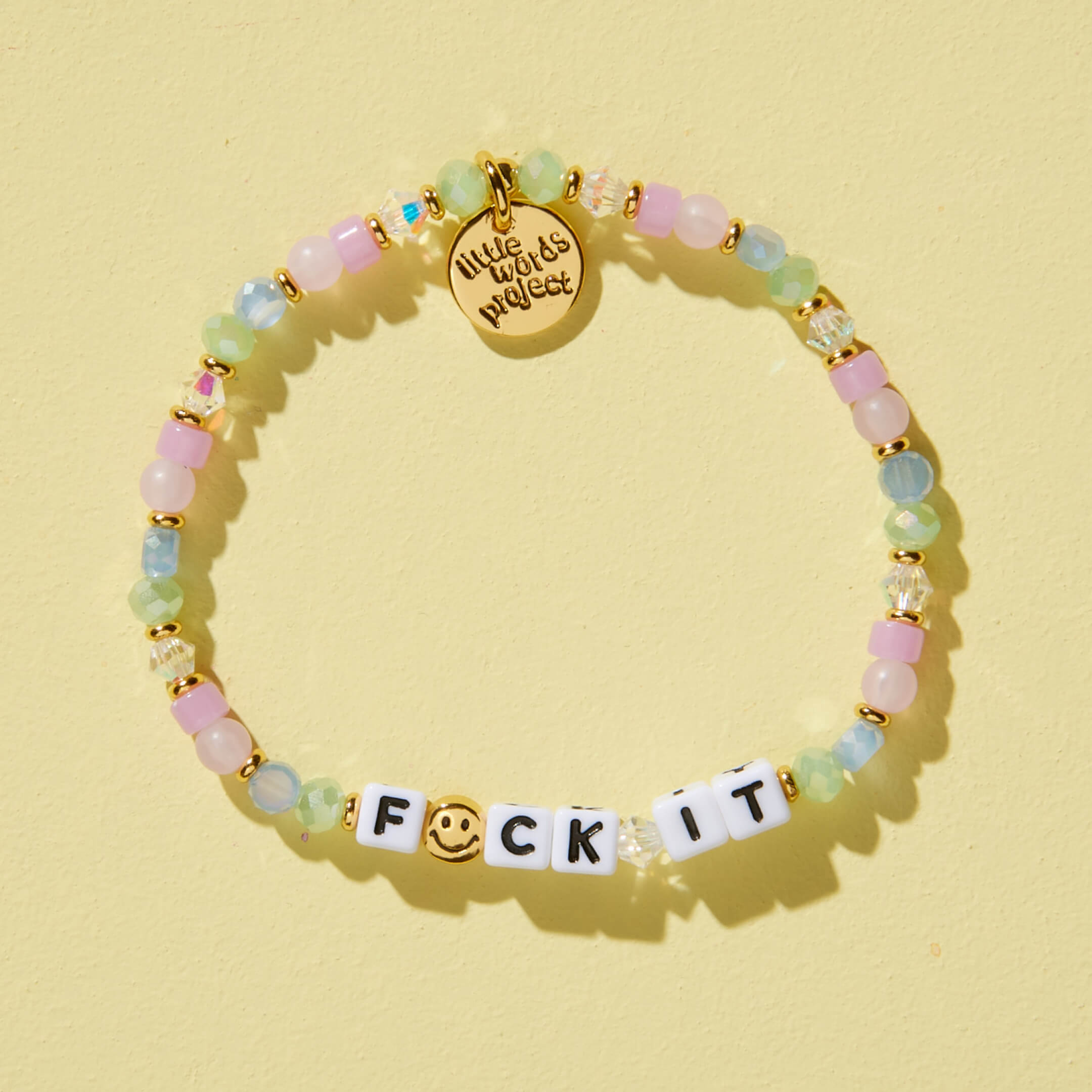 Multicolored beaded bracelet with a gold charm and letter beads on a yellow background