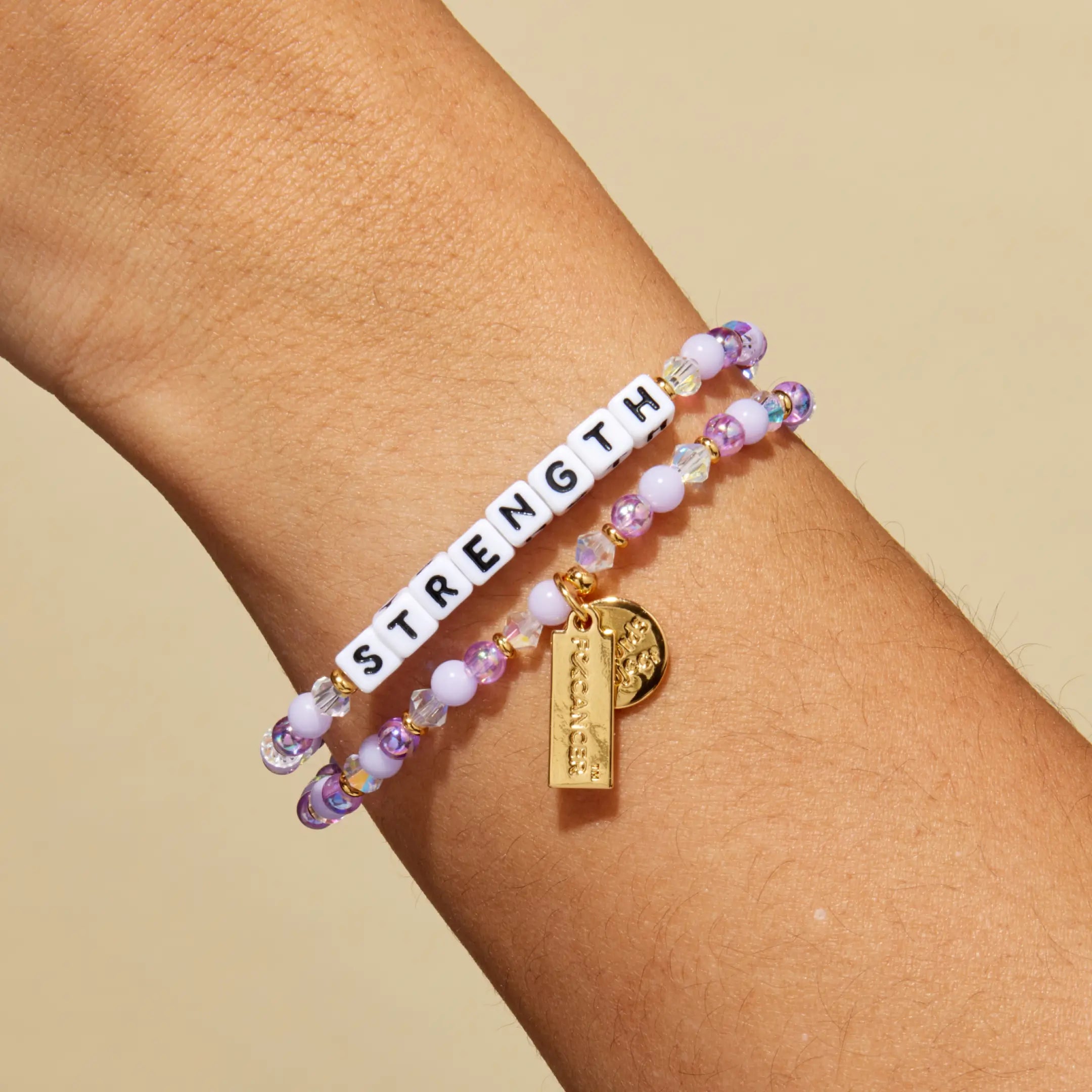 Bracelet with 'STRENGTH' on a wrist against a beige background