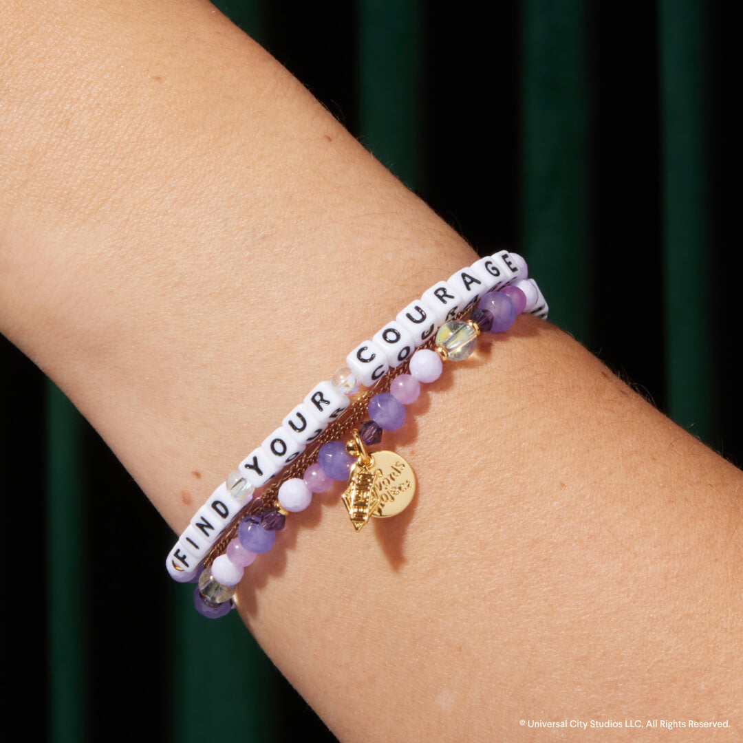 Bracelet with motivational message on wrist against a dark background
