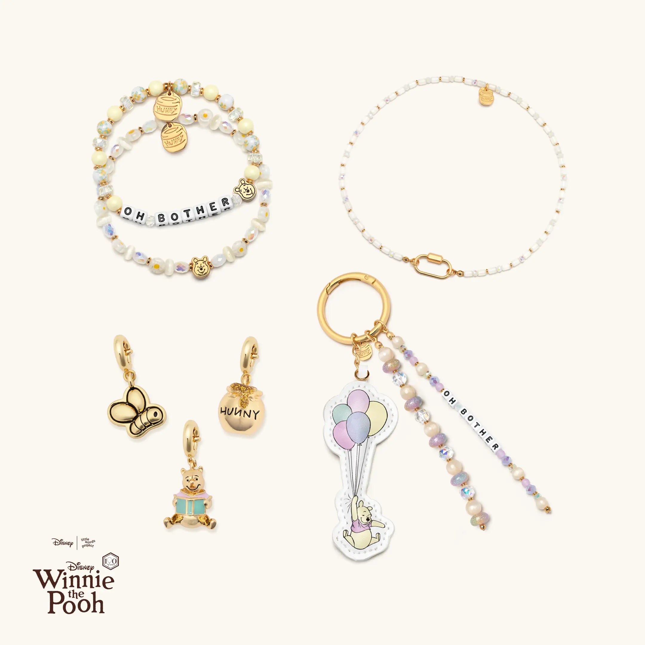 Collection of Winnie the Pooh-themed jewelry and bag charm on a white background with Disney logo.