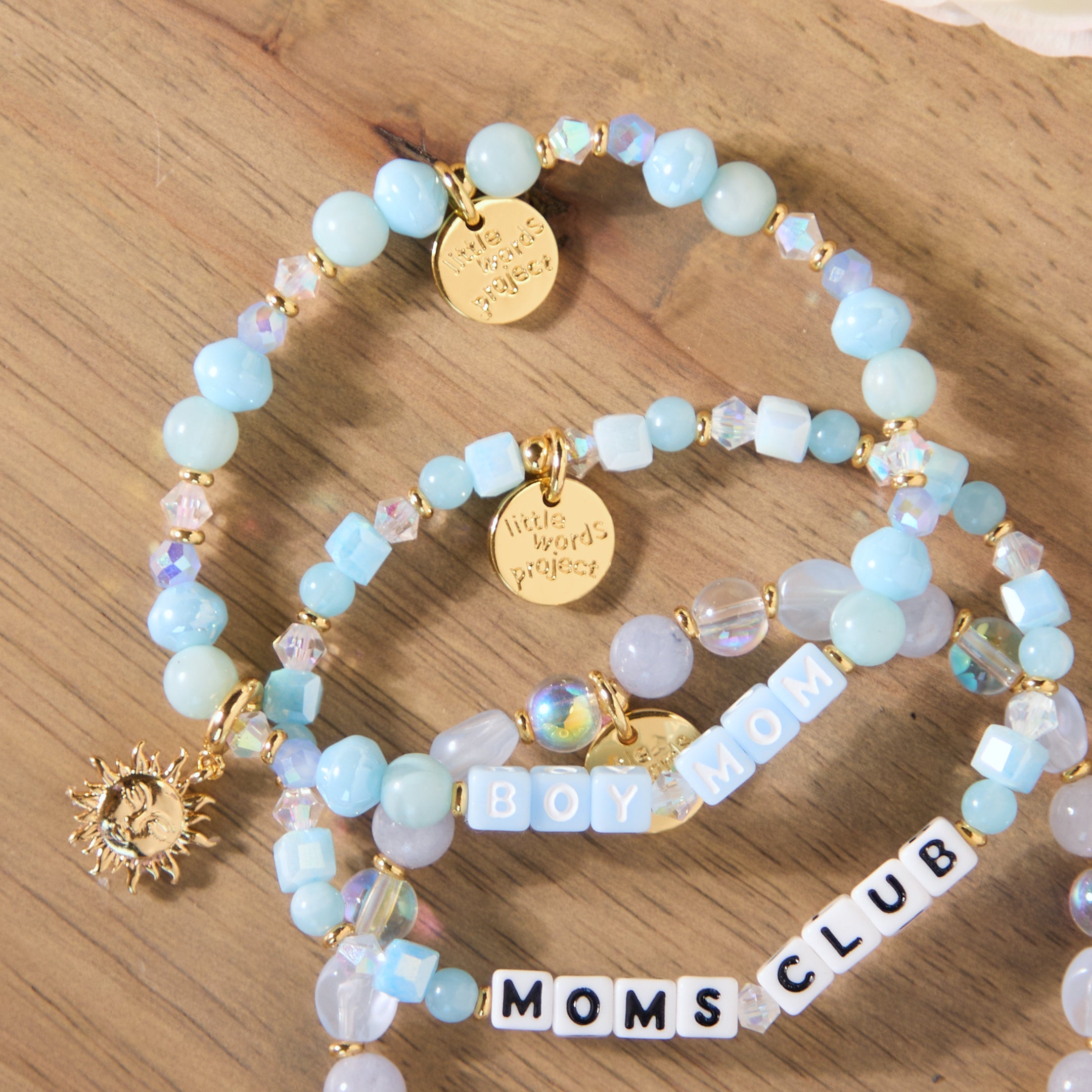 Stack of beaded bracelets with charms on a wooden surface