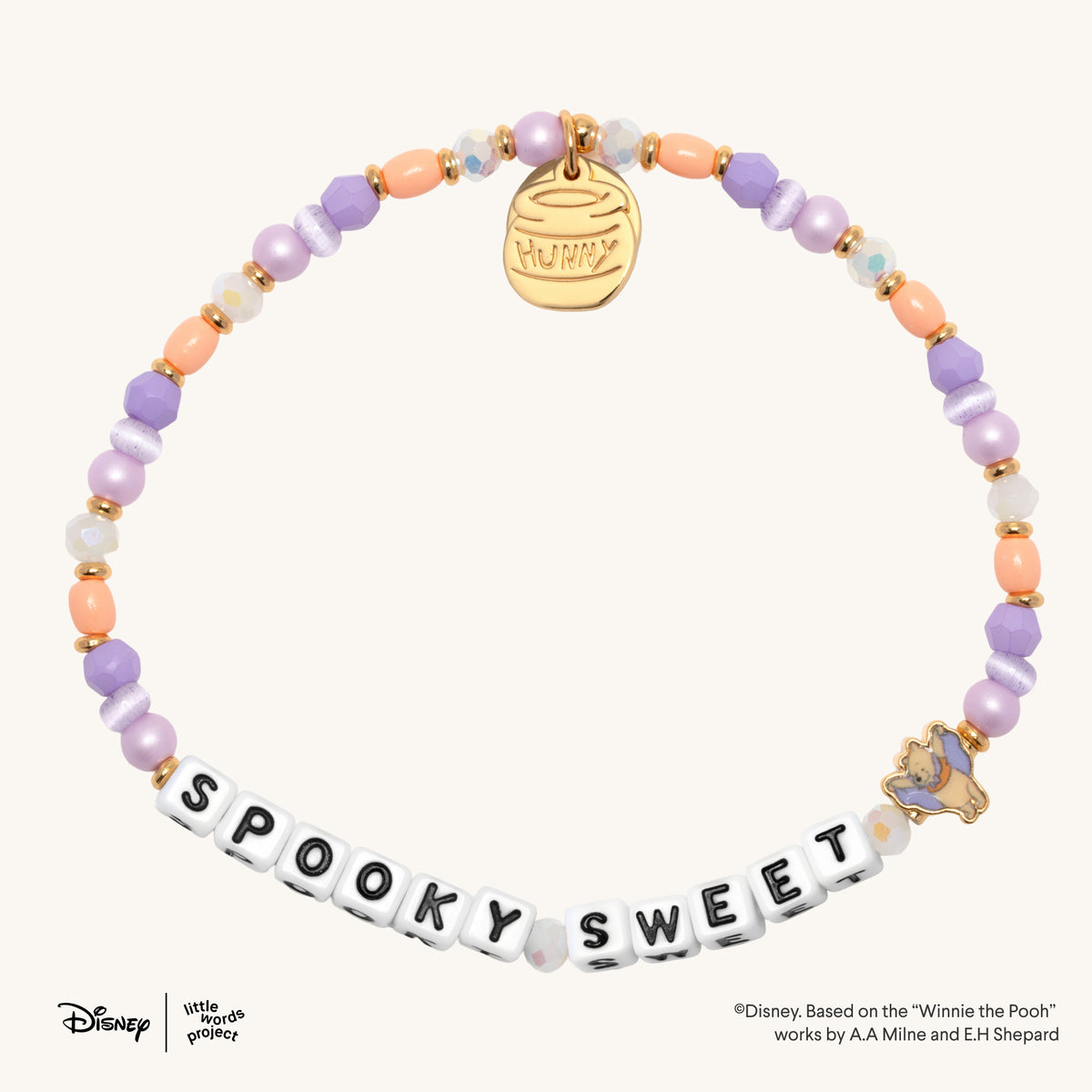 Spooky Sweet Disney's Winnie the Pooh bracelet in the Spooky Sweetie bead pattern, white letter beads with lavender, peach, and pearl beads, gold hunny pot charm and Winnie the Pooh vampire casted bead, flat-lay on cream background