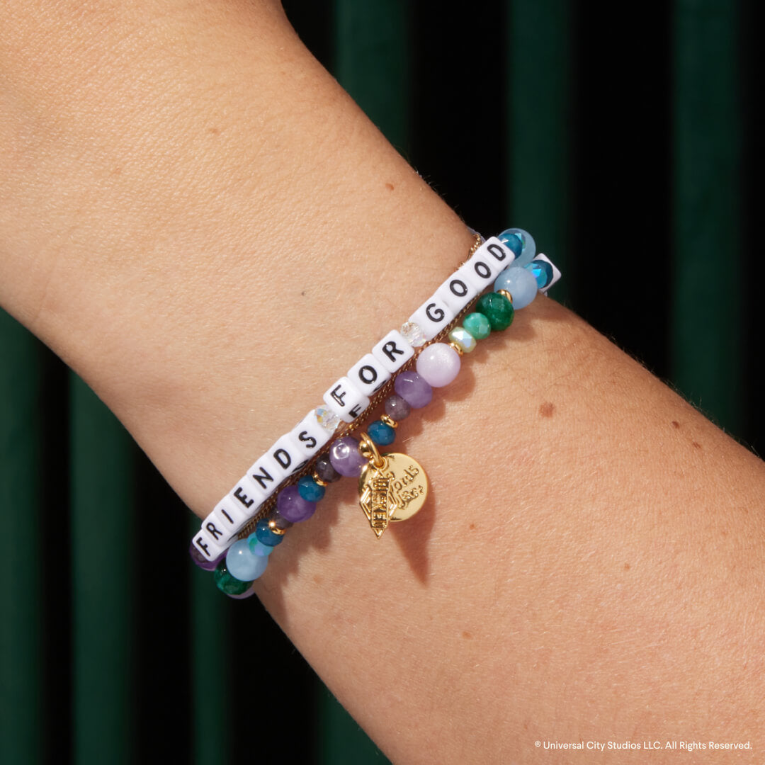Bracelet with 'Friends for Good' beads on a wrist against a dark background