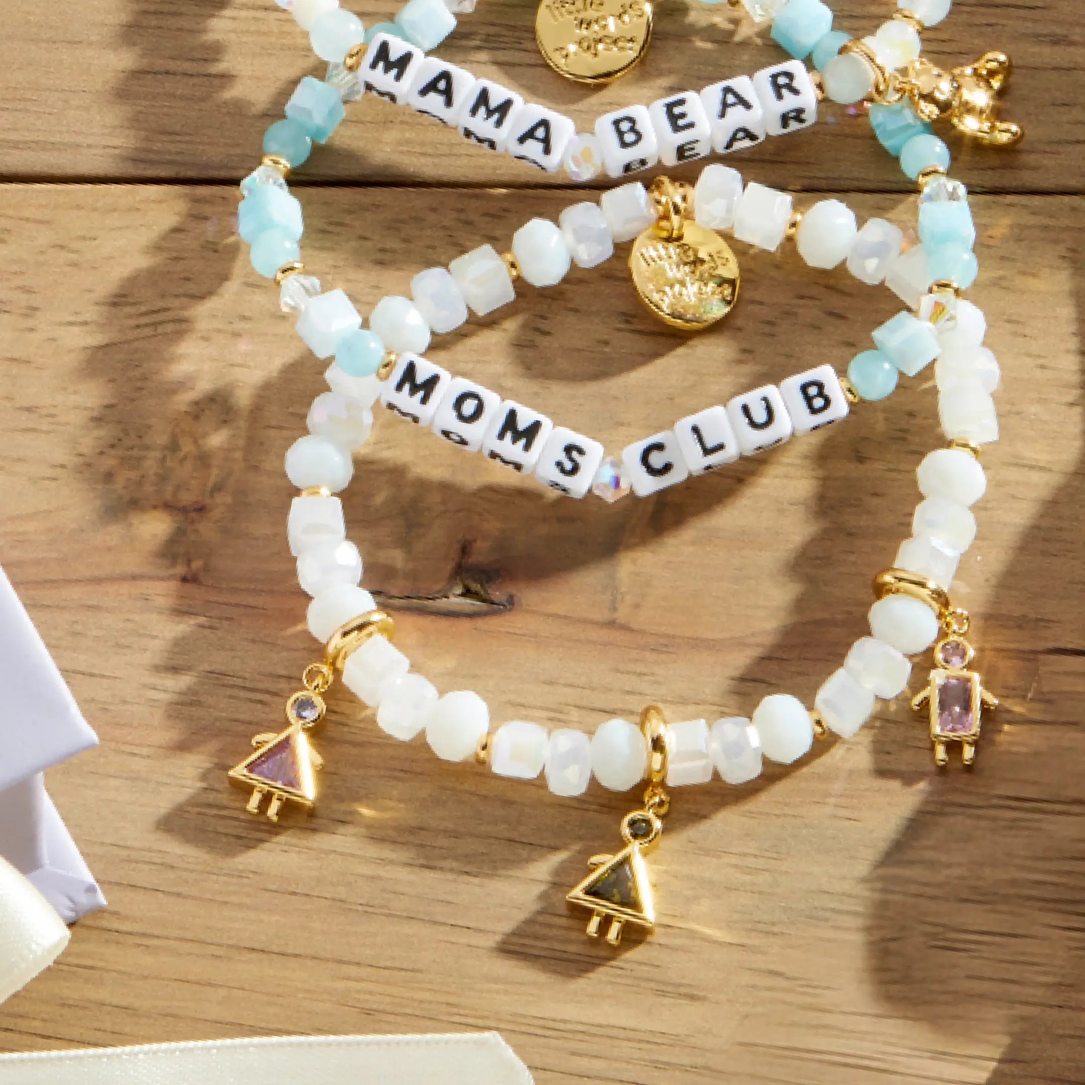 Set of beaded bracelets with 'Mama Bear' and 'Moms Club' on a wooden surface