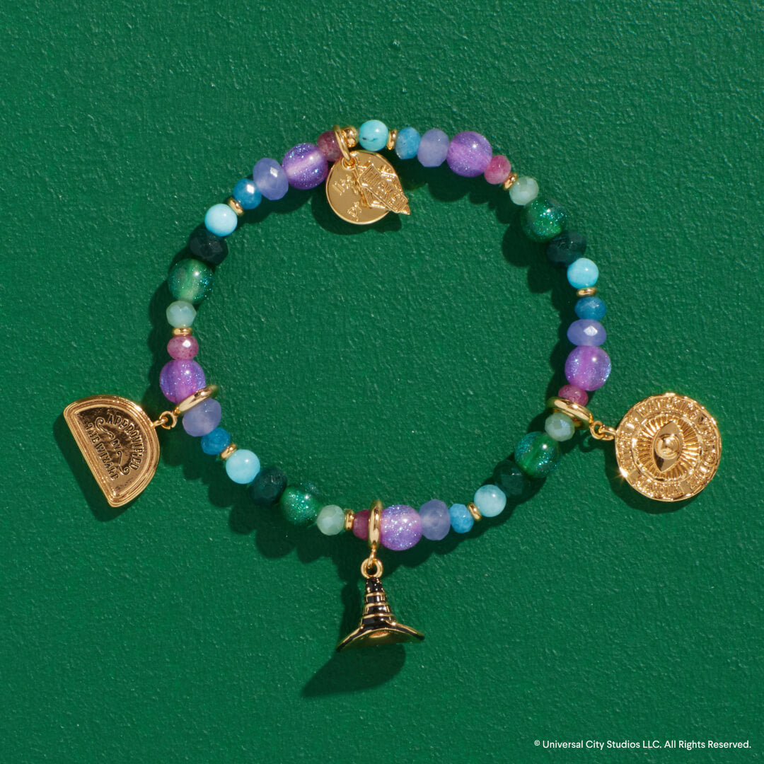 Beaded bracelet with gold charms on a green background