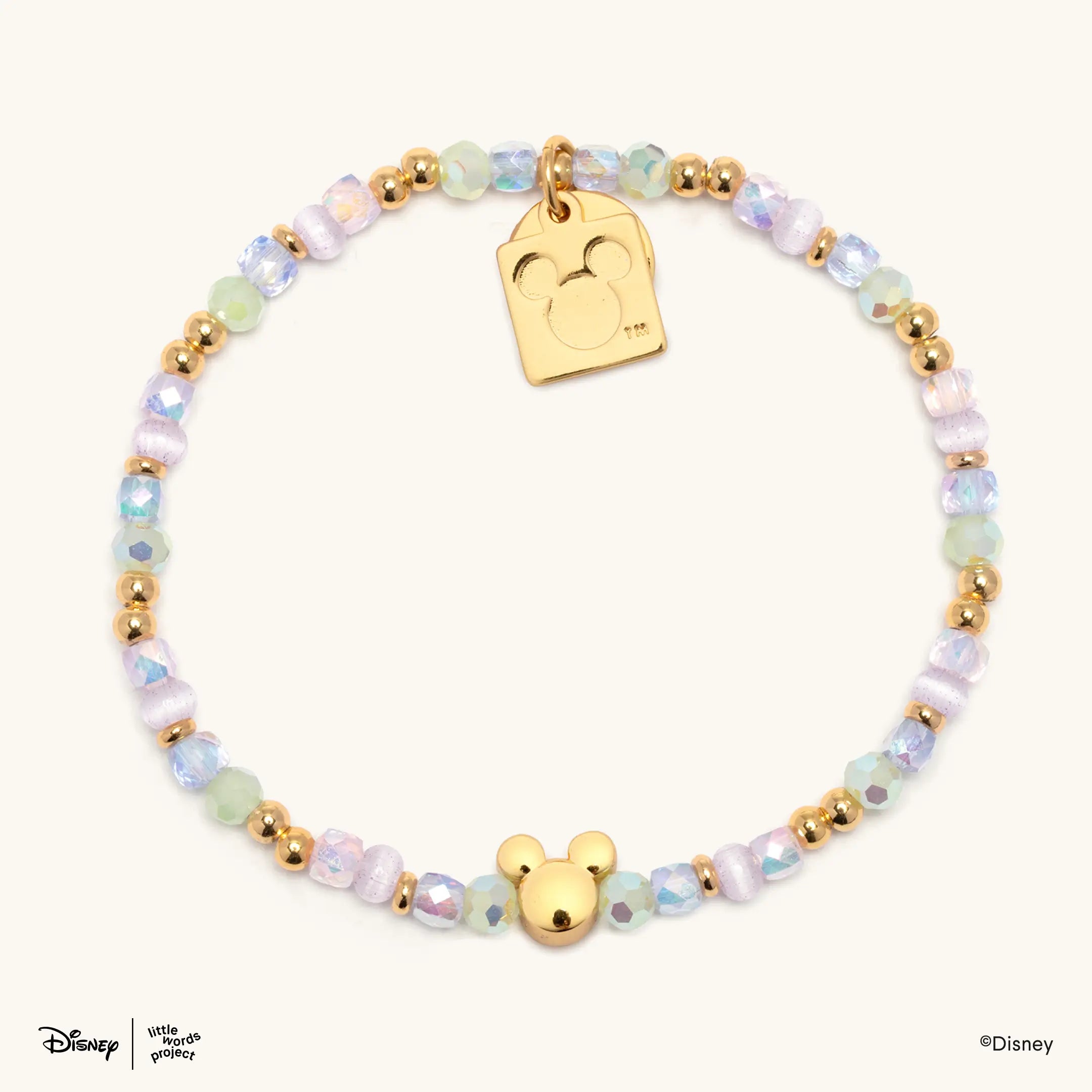 Mickey Mouse Bracelet Base from Disney Mickey and Friends, flat lay on cream with pastel iridescent beads, a gold Mickey Mouse bead and a gold plated casted Mickey Mouse tag charm