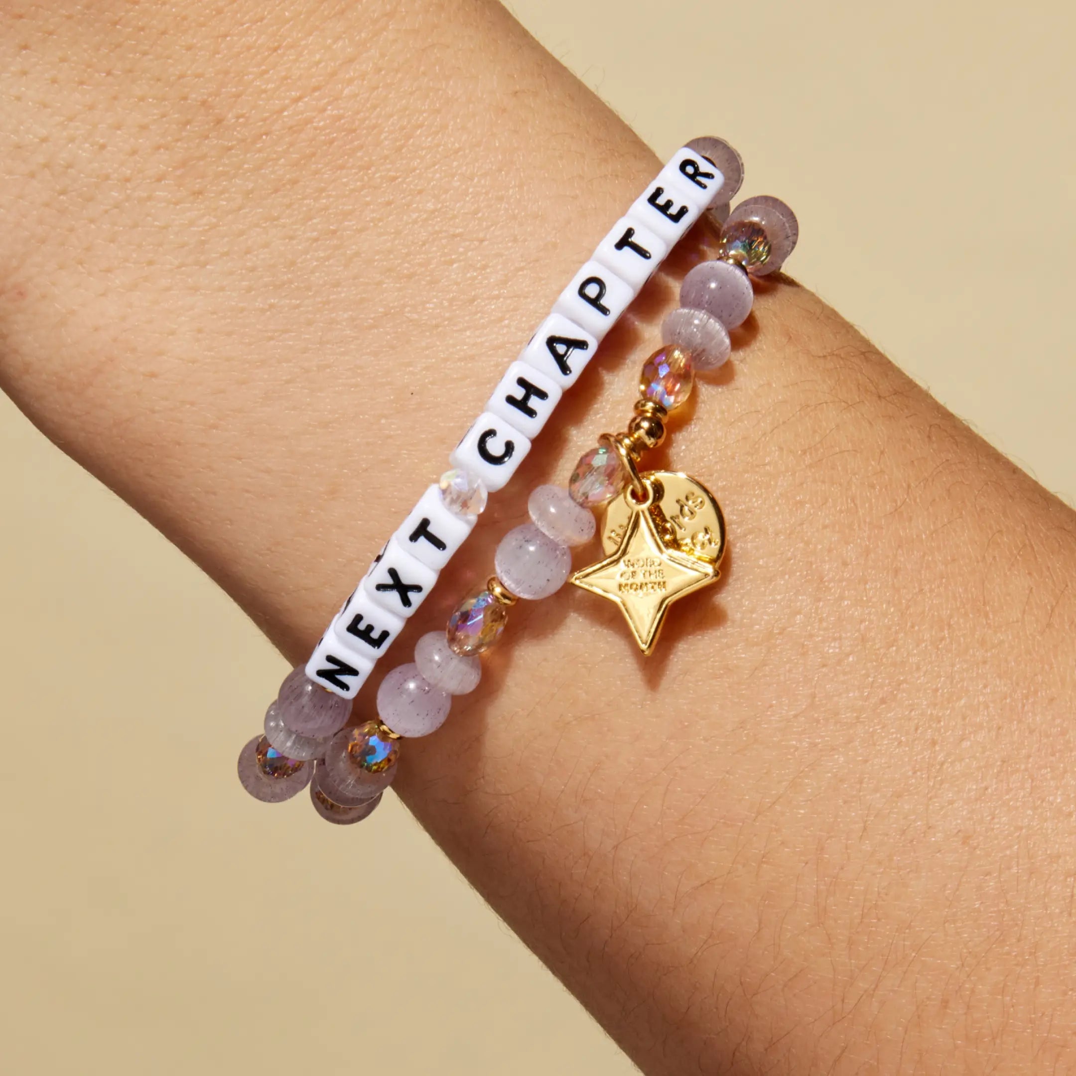 Bracelet with 'Next Chapter' on a wrist against a beige background
