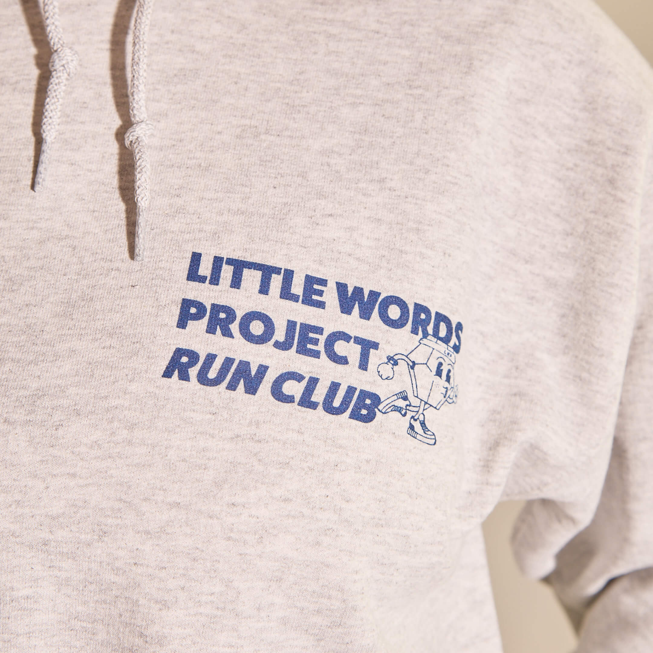 Beige hoodie with blue text and logo on a beige background