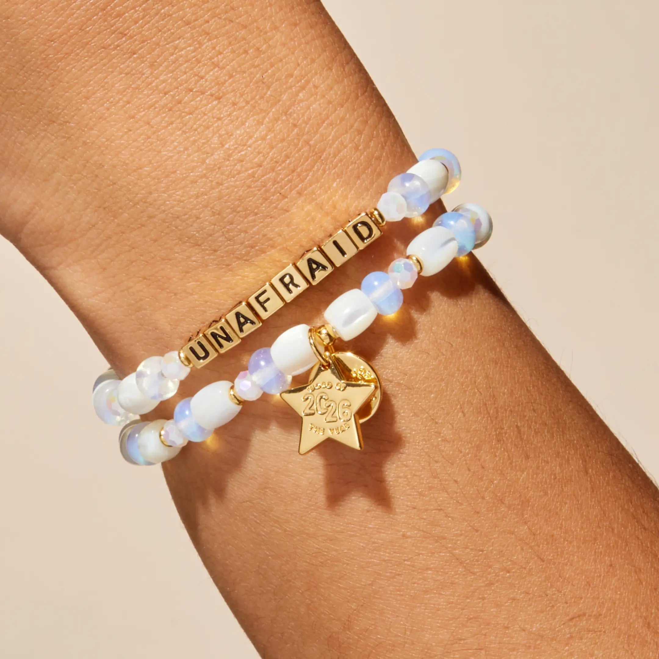Bracelet with 'UNAFRAID' on a wrist against a beige background