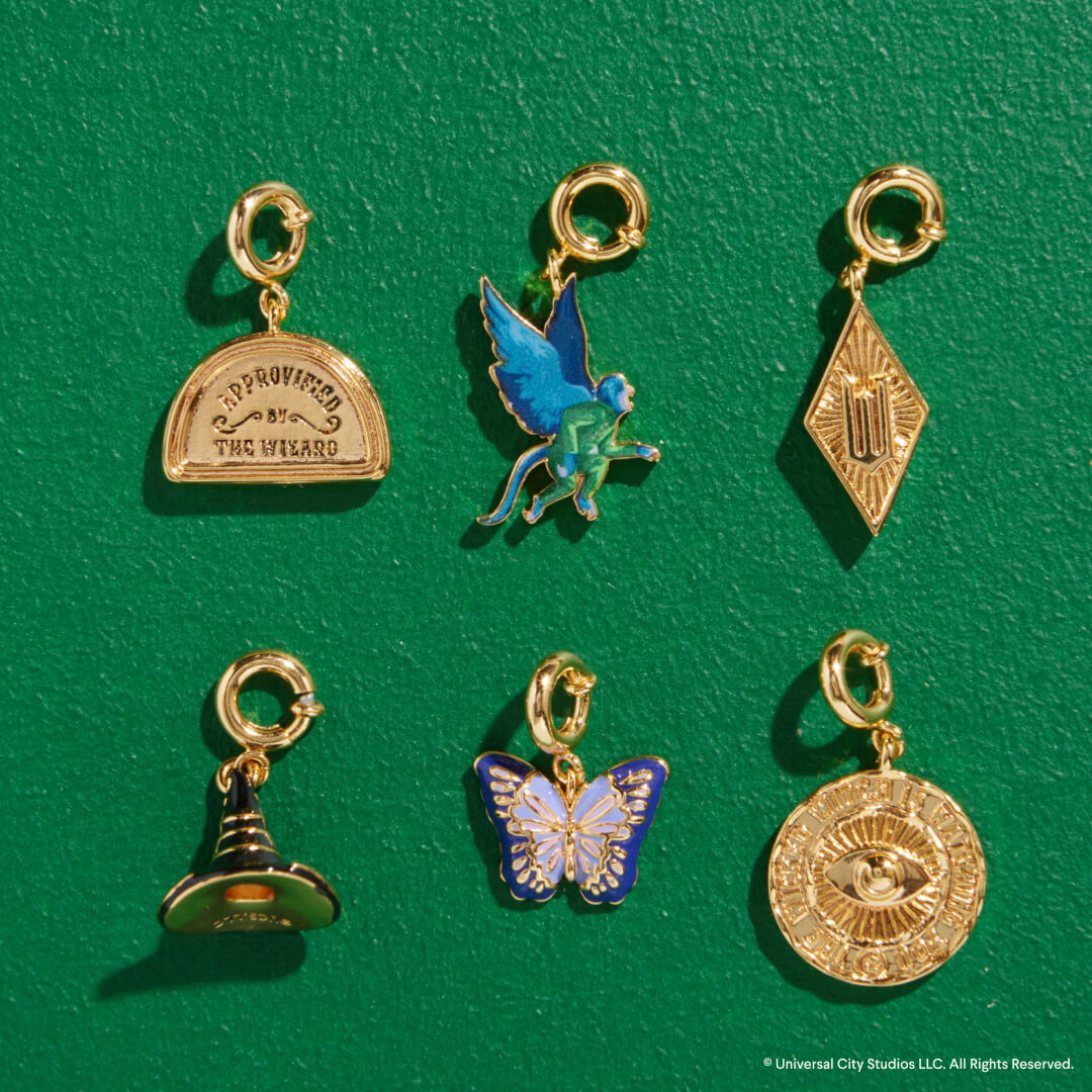 Set of six gold and enamel charms on a green background