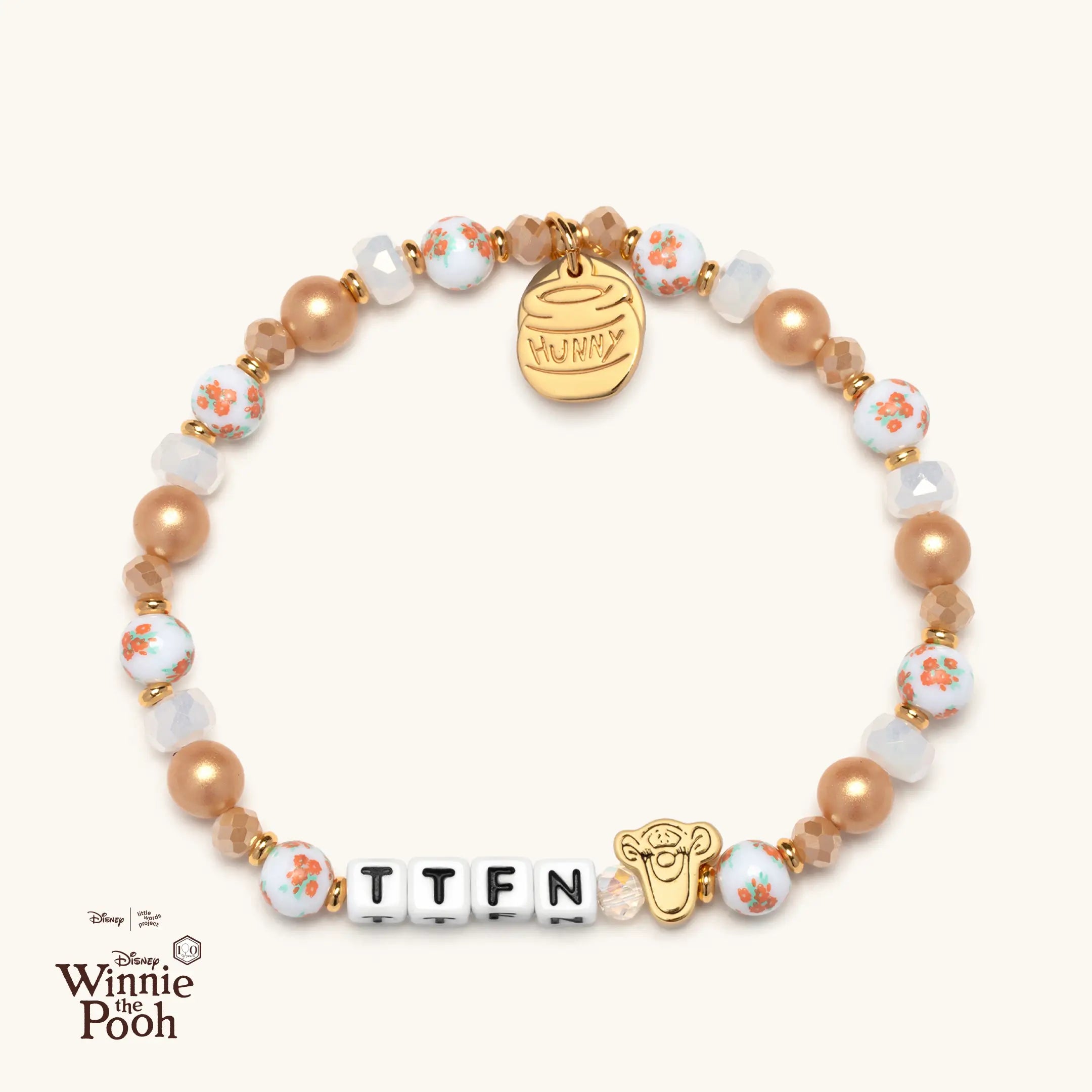 Bracelet with orange and white floral beads and TTFN word on a white background.