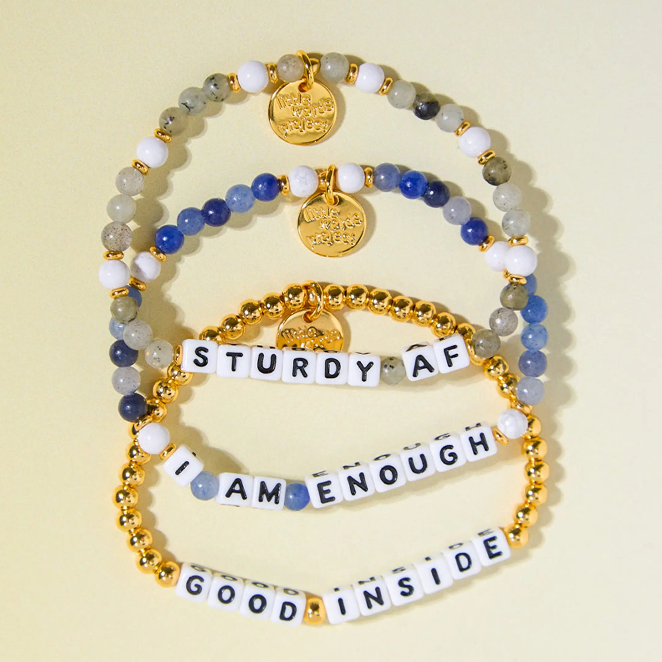 Stack of beaded bracelets with motivational phrases on a yellow background