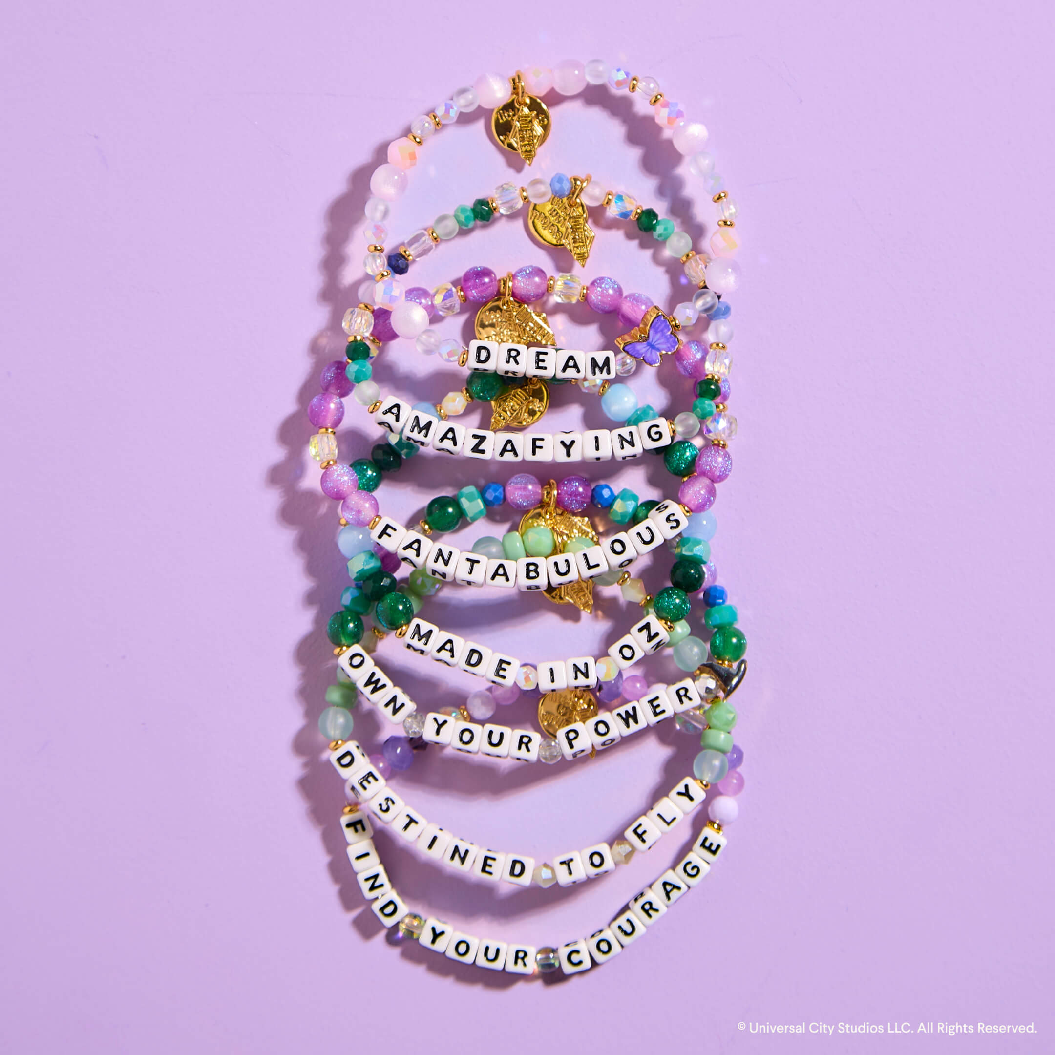 Stack of colorful beaded bracelets with motivational phrases on a purple background