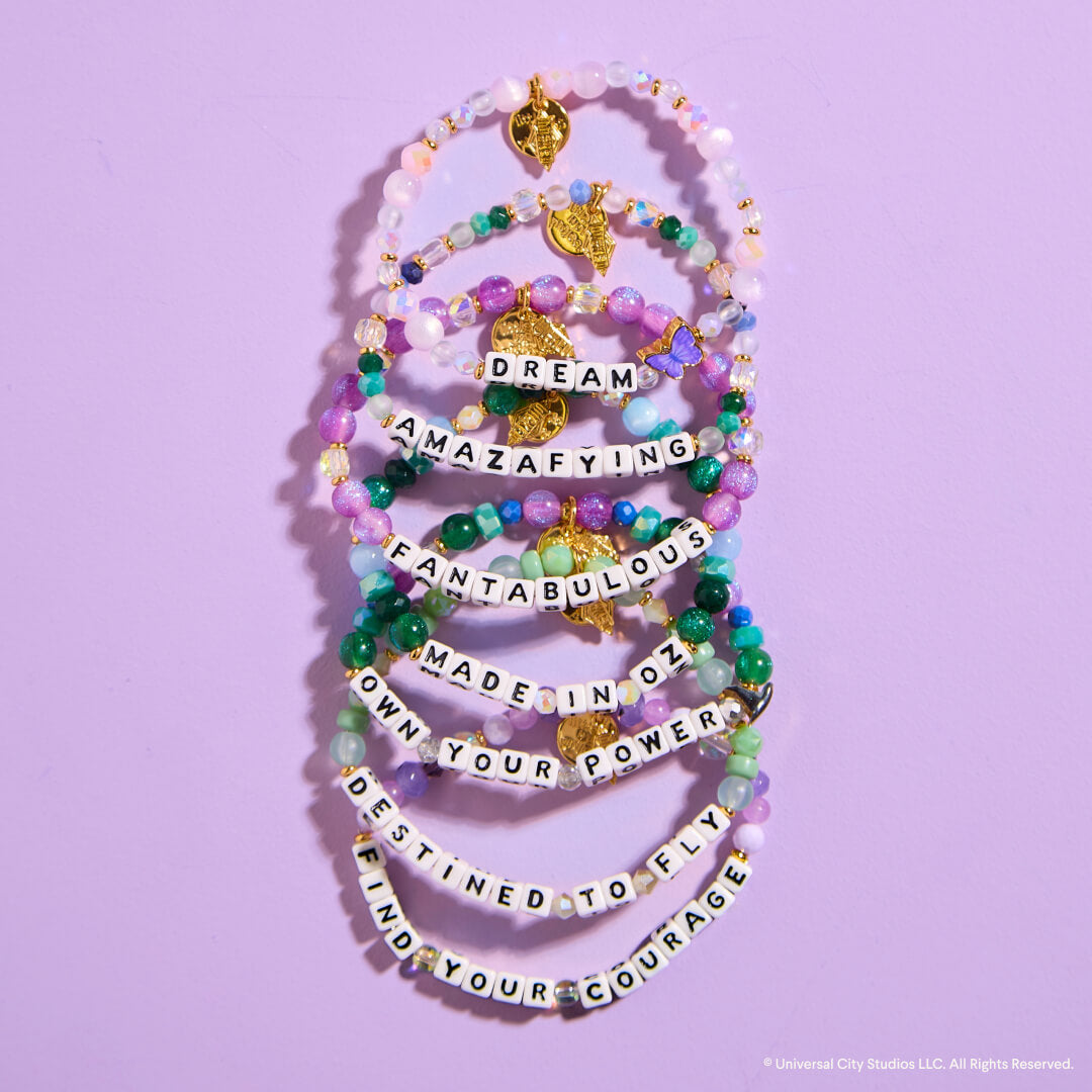 Stack of colorful beaded bracelets with motivational phrases on a purple background