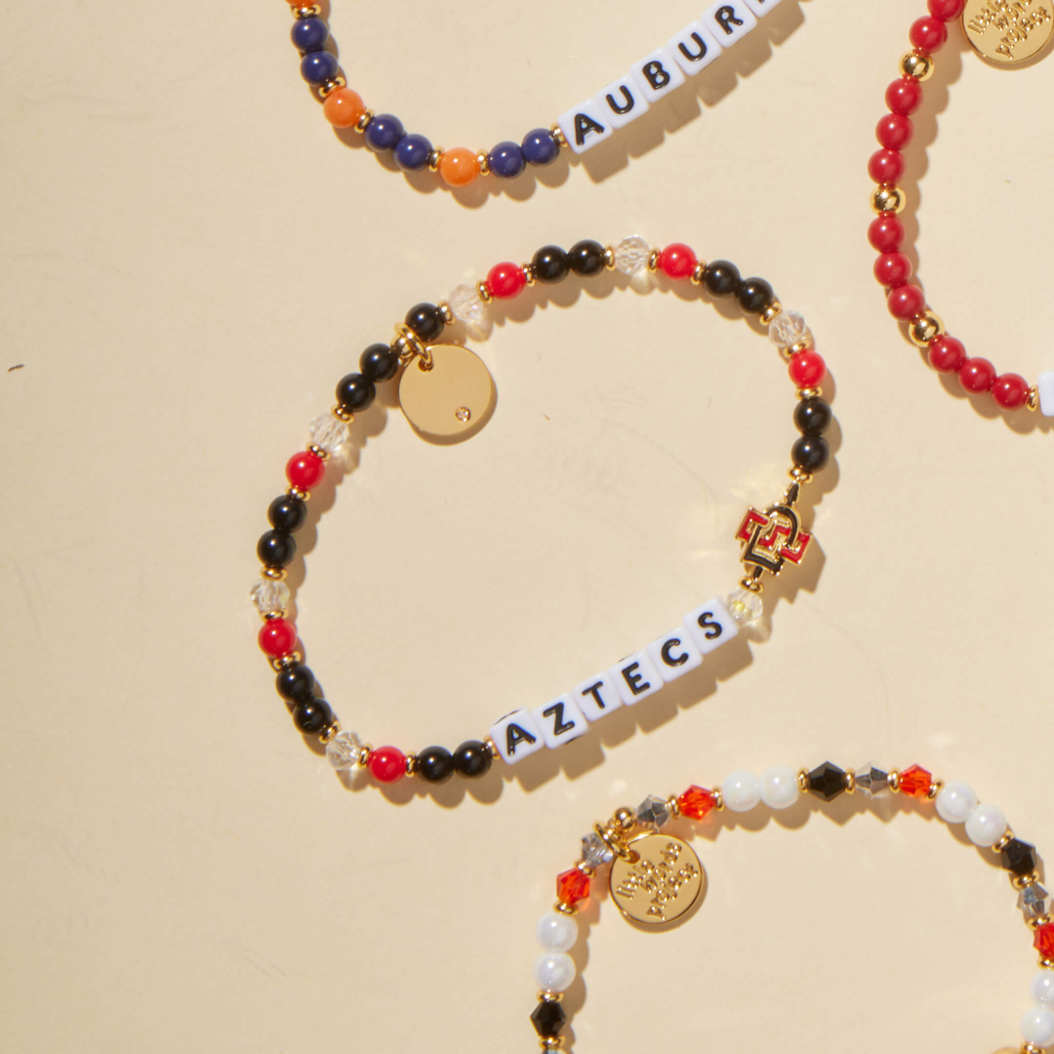 Colorful beaded bracelets with 'AZTECS' on a beige background