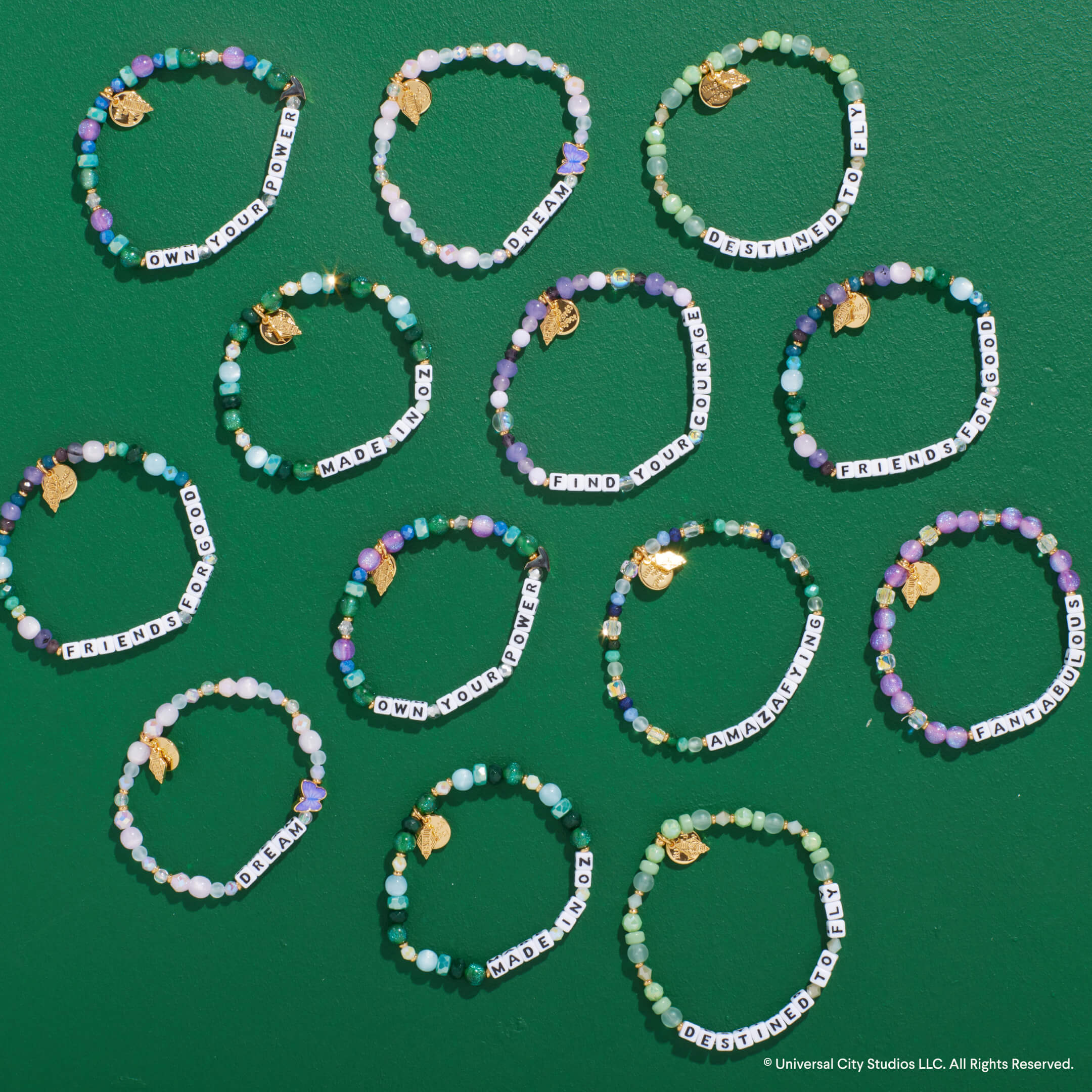 Multiple beaded bracelets with word charms on a green background