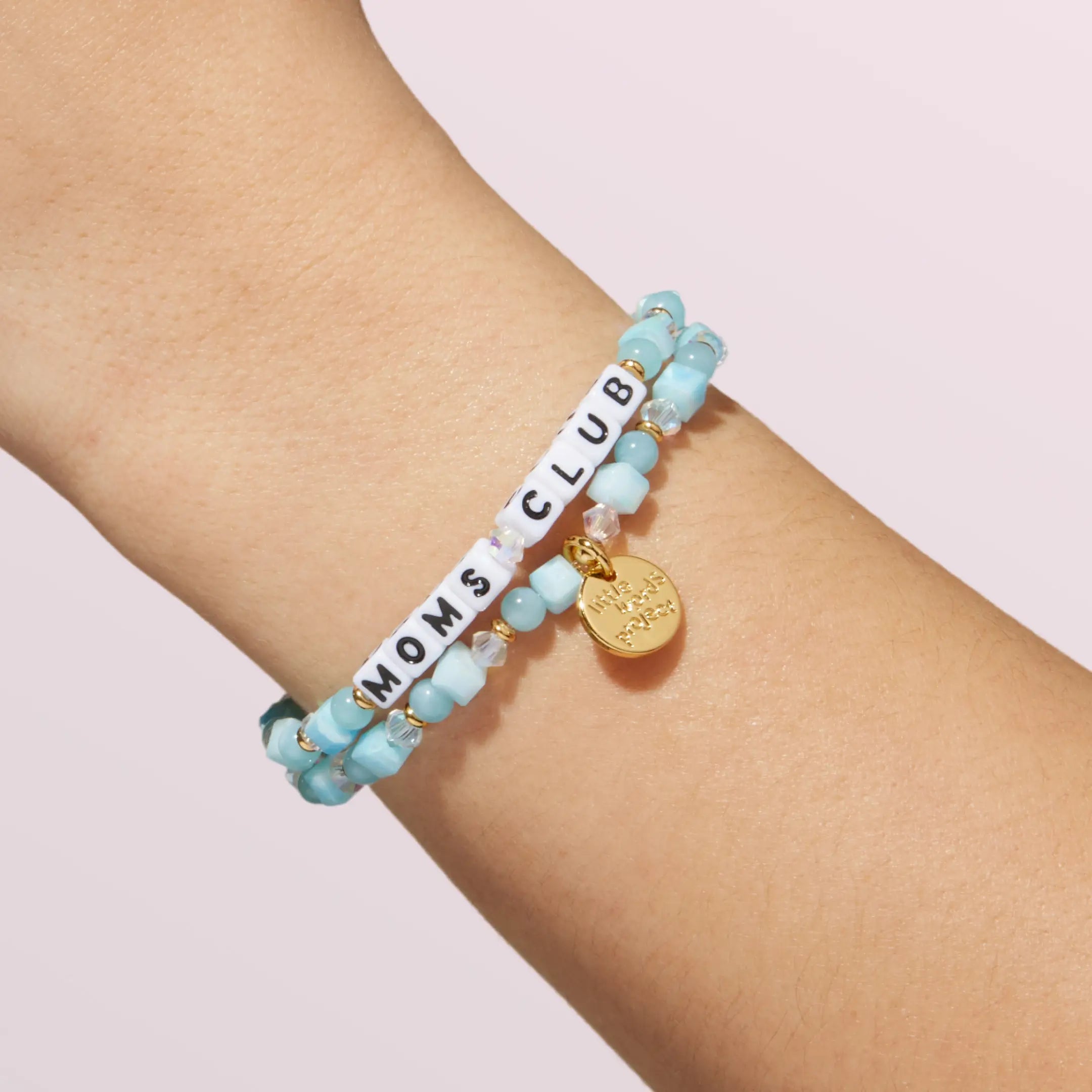 Turquoise beaded bracelet with 'Moms Club' on a wrist against a light background