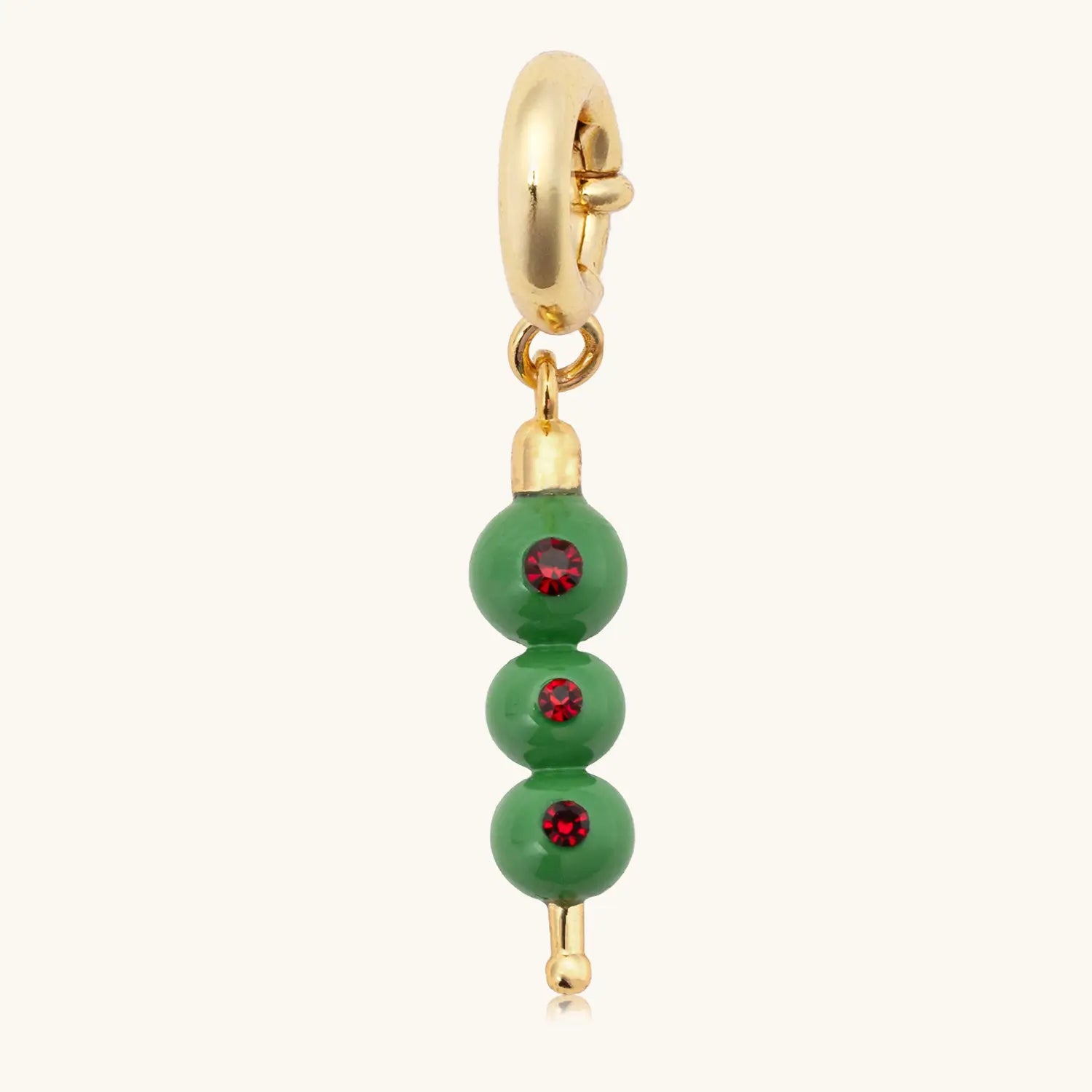 Gold charm with green olives and red stones on a white background