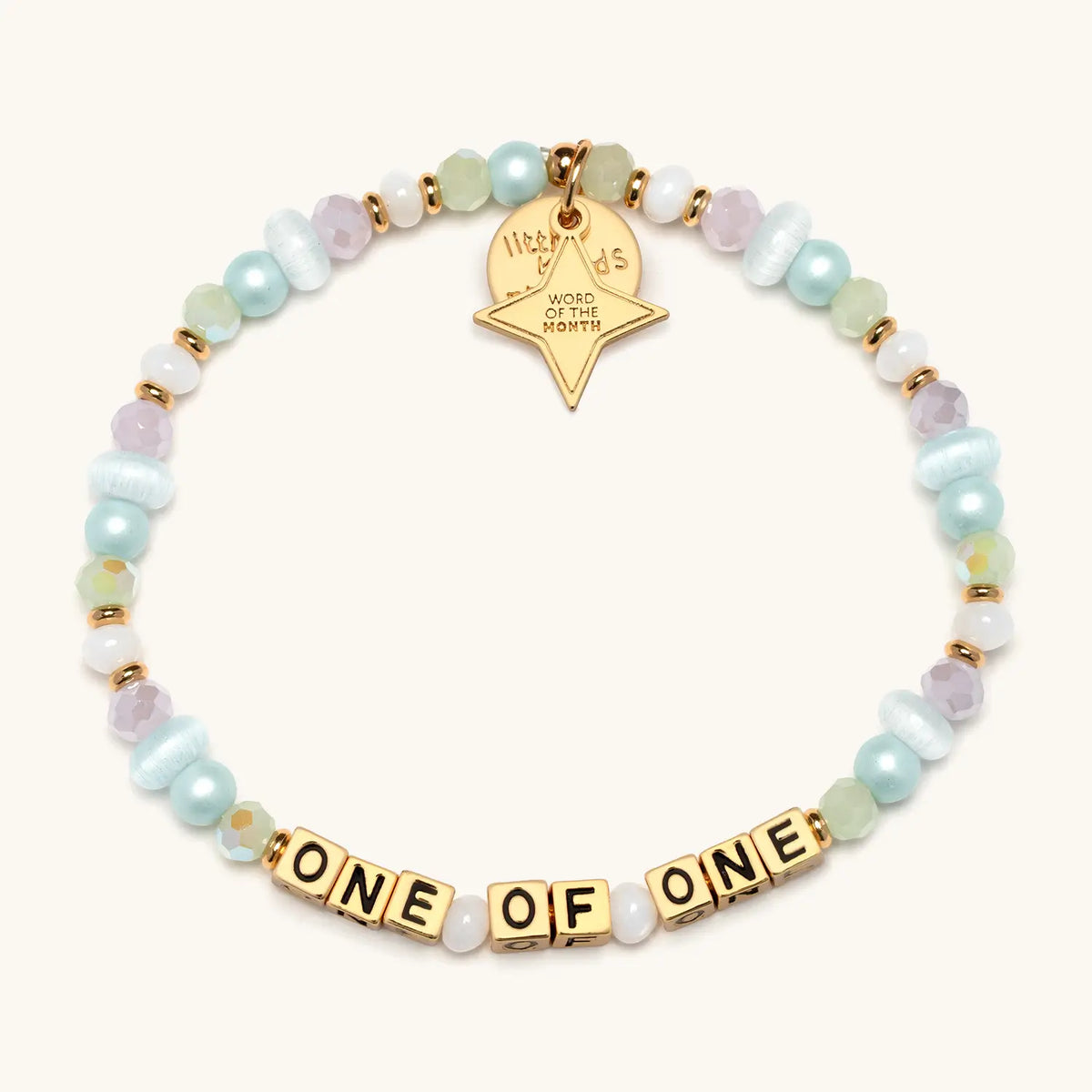 One Of One July WOTM bracelet with white beads and gold hardware, product flat-lay