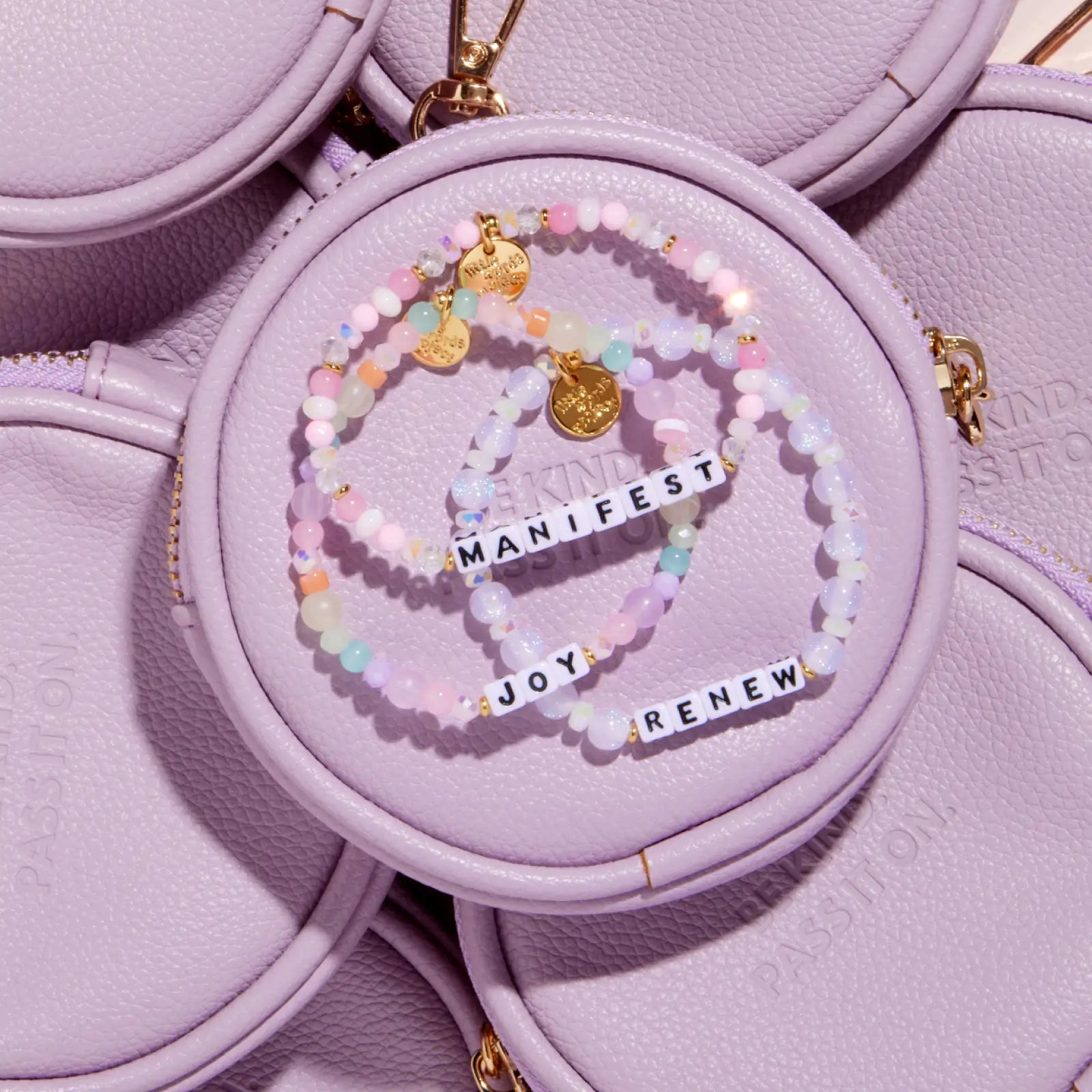 Set of beaded bracelets with motivational charms on a purple surface