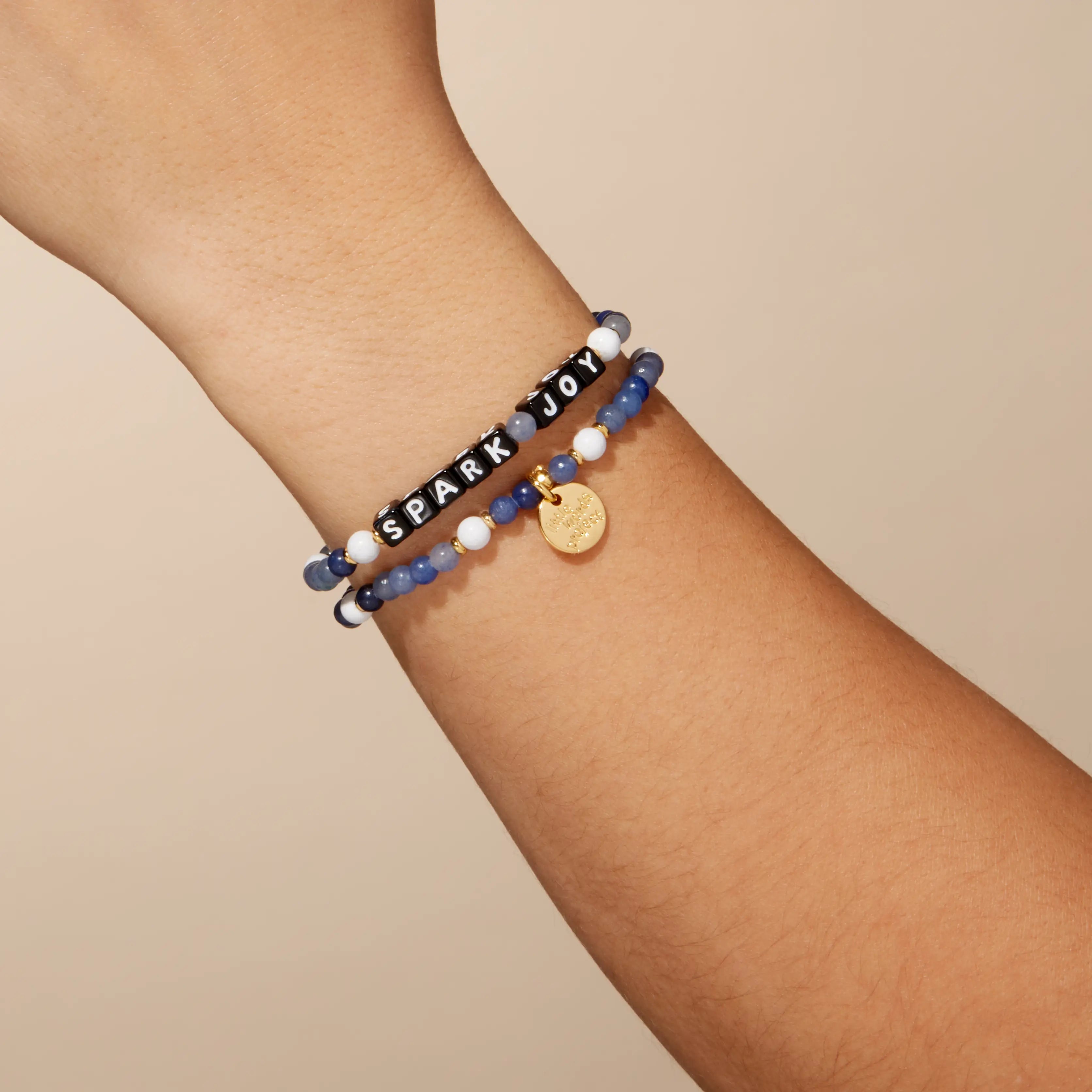 Bracelet with 'Spark Joy' on a wrist against a beige background