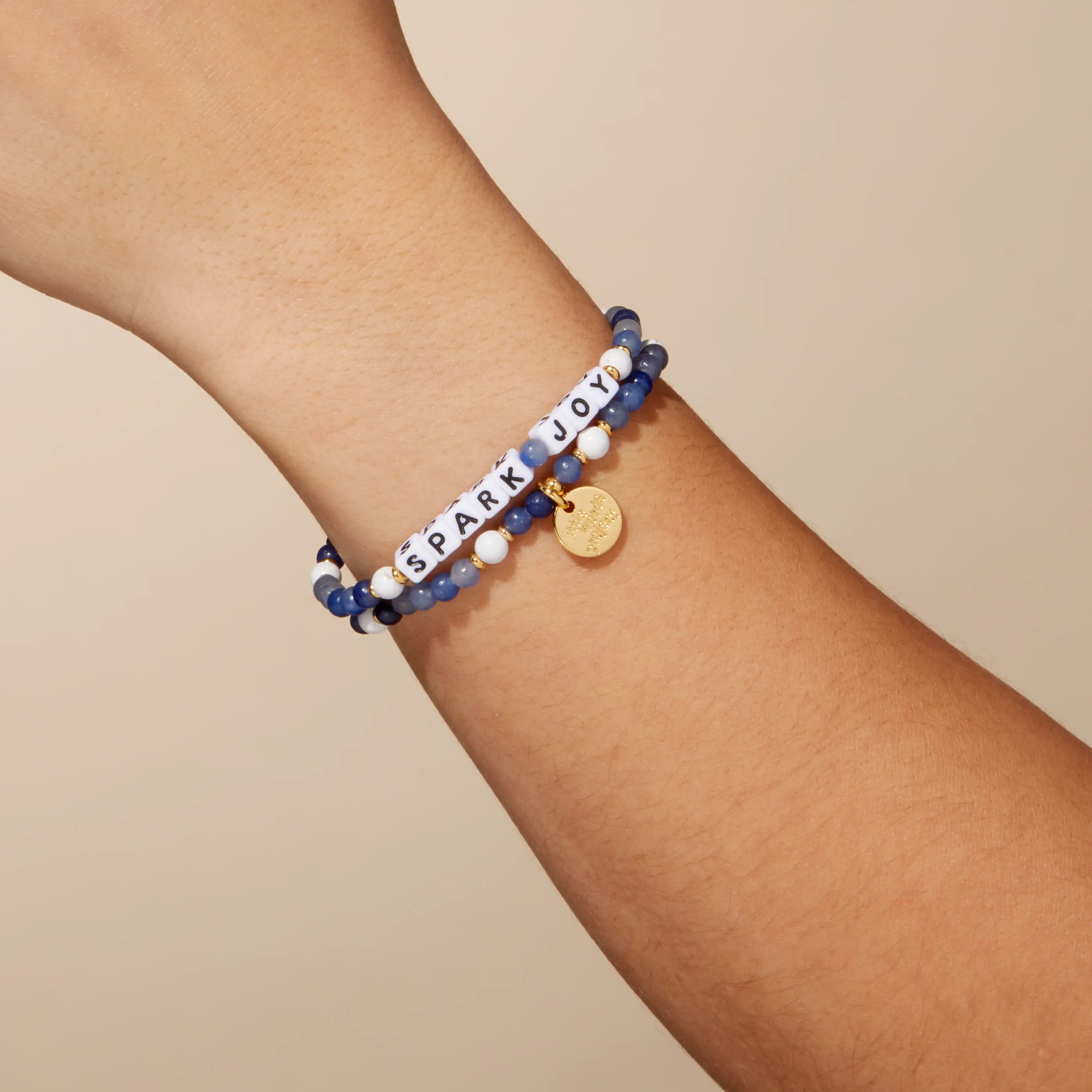 Bracelet with motivational message on wrist against a beige background